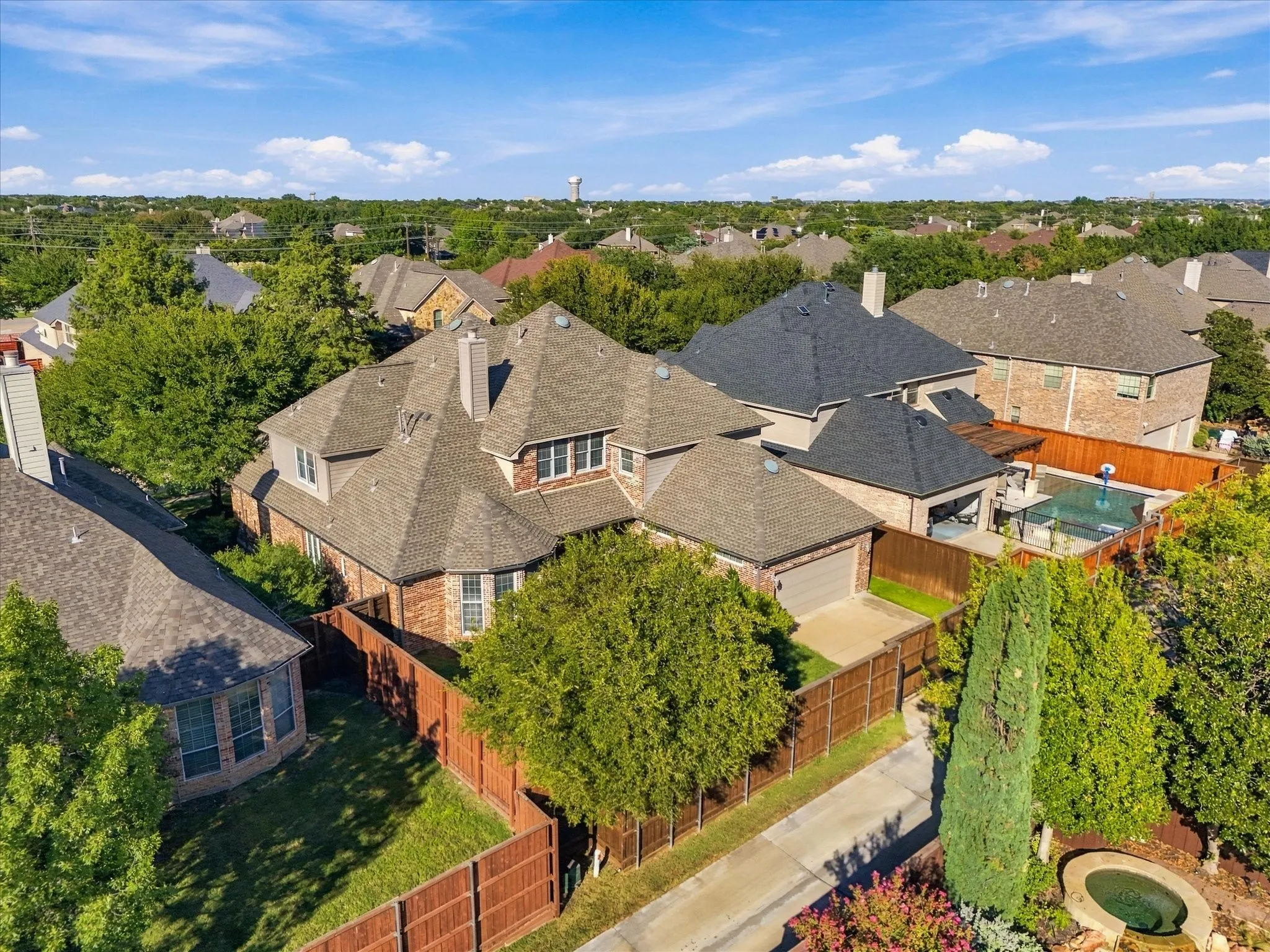 Brick exterior with multiple gables, attached garage, private backyard with a pool, and mature perimeter trees
