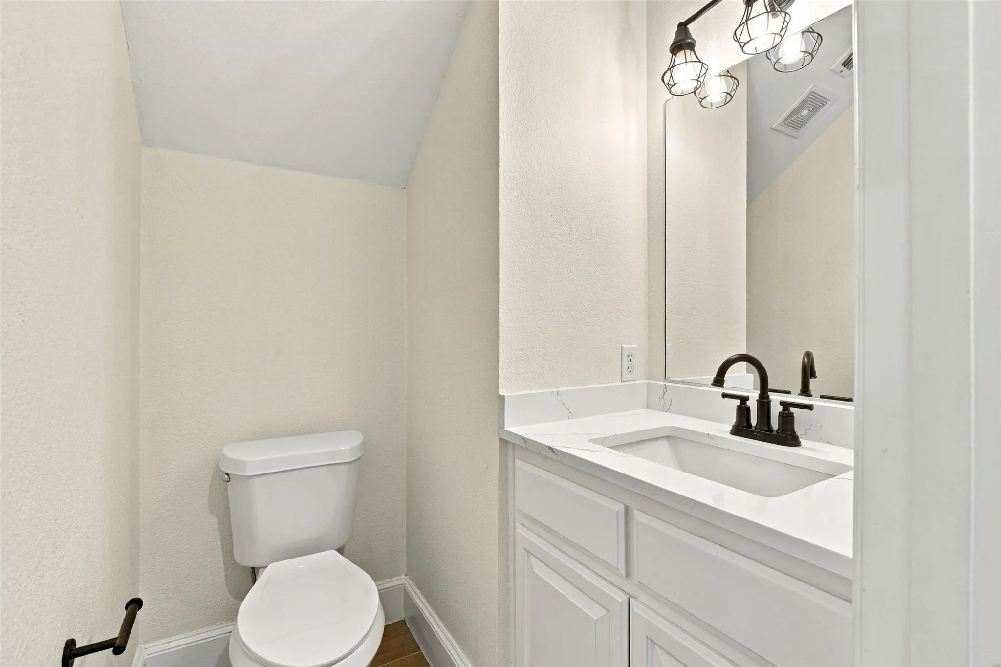 White vanity with a rectangular undermount sink, dark bronze faucet, and a large wall-mounted mirror