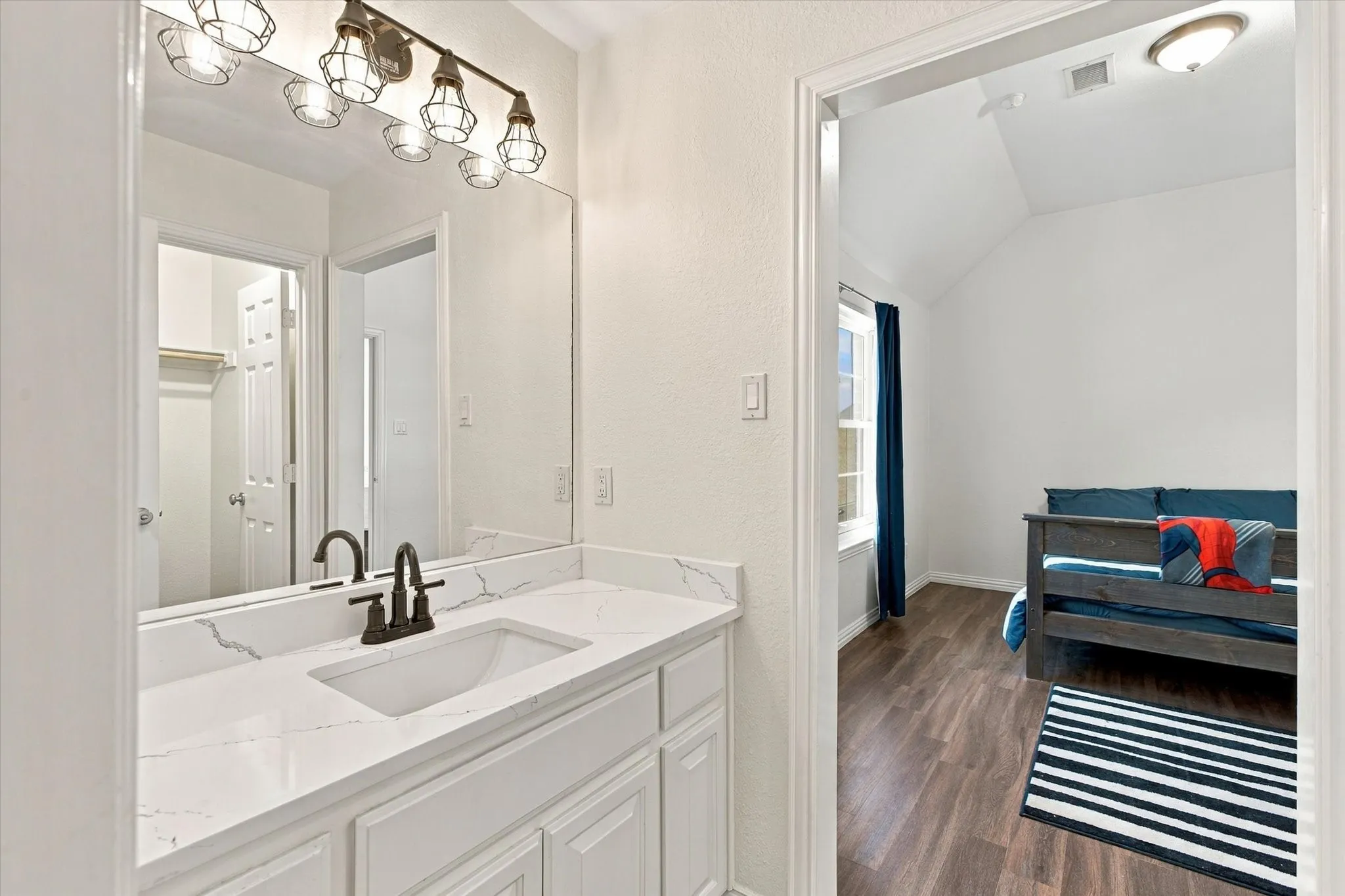 Vanity with a rectangular undermount sink, a stone-finish countertop, and a dark bronze faucet