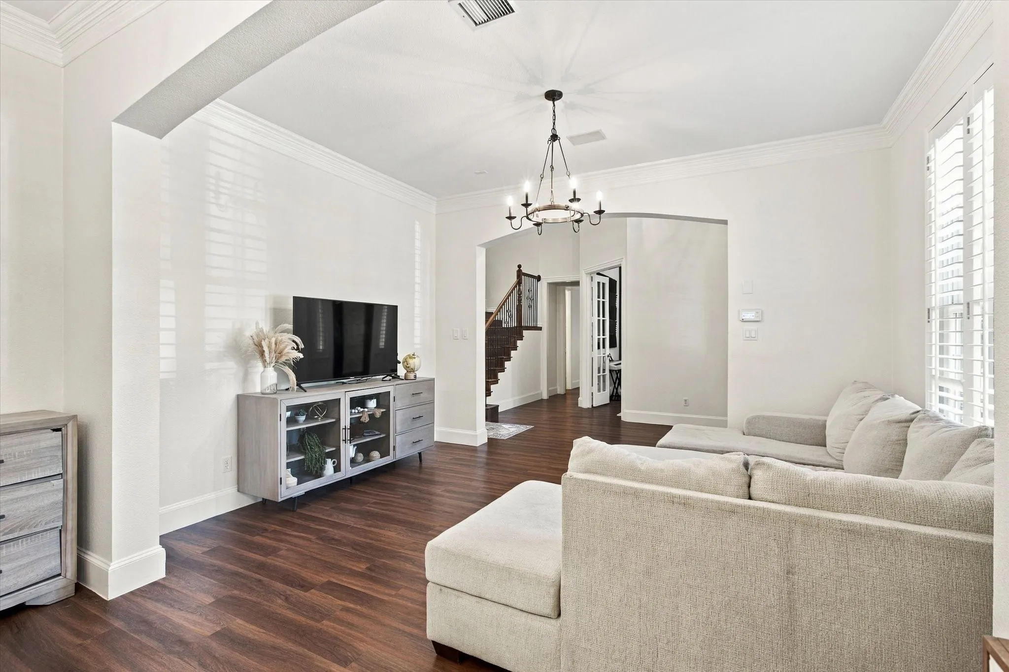 Hardwood-finish flooring, crown molding, plantation shutters, recessed lighting, and a chandelier