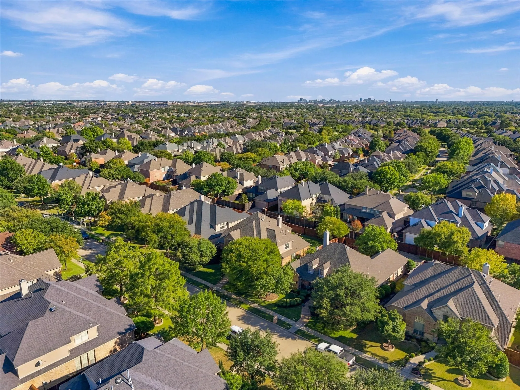 Residential neighborhood featuring detached homes, tree-lined streets, and a distant city skyline