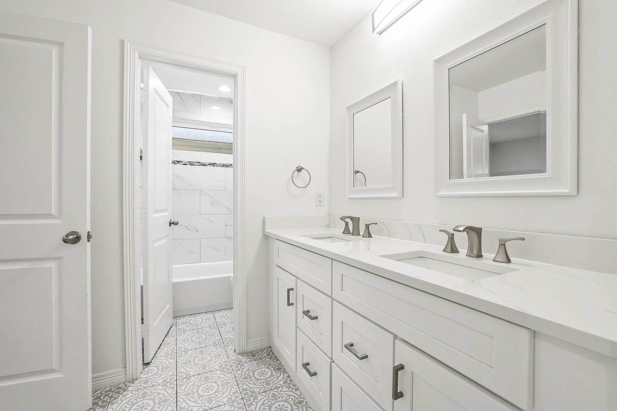Dual vanity with white shaker-style cabinetry, undermount sinks, and brushed nickel fixtures