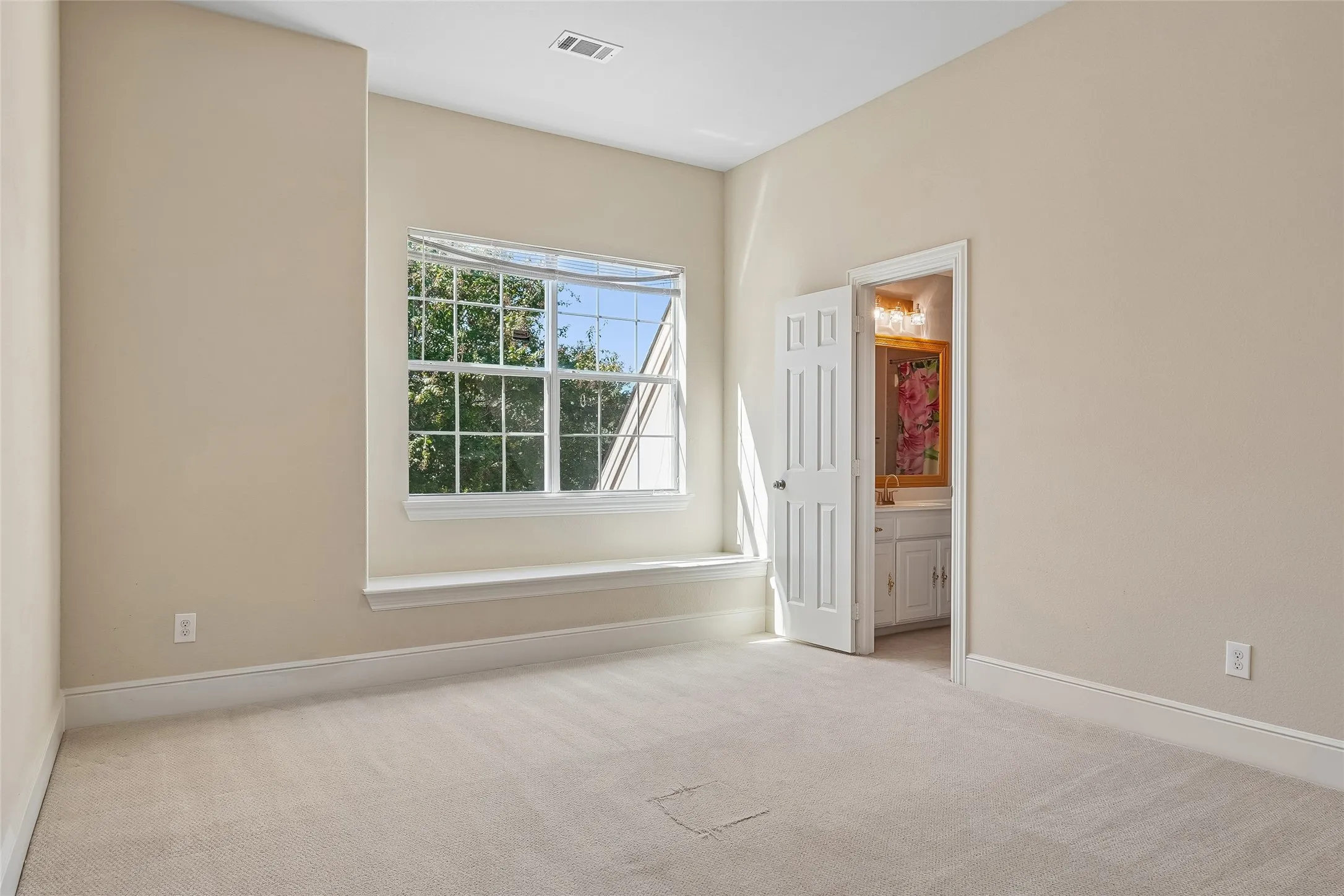 Carpeted room with a multi-pane window, window ledge, and a panel door