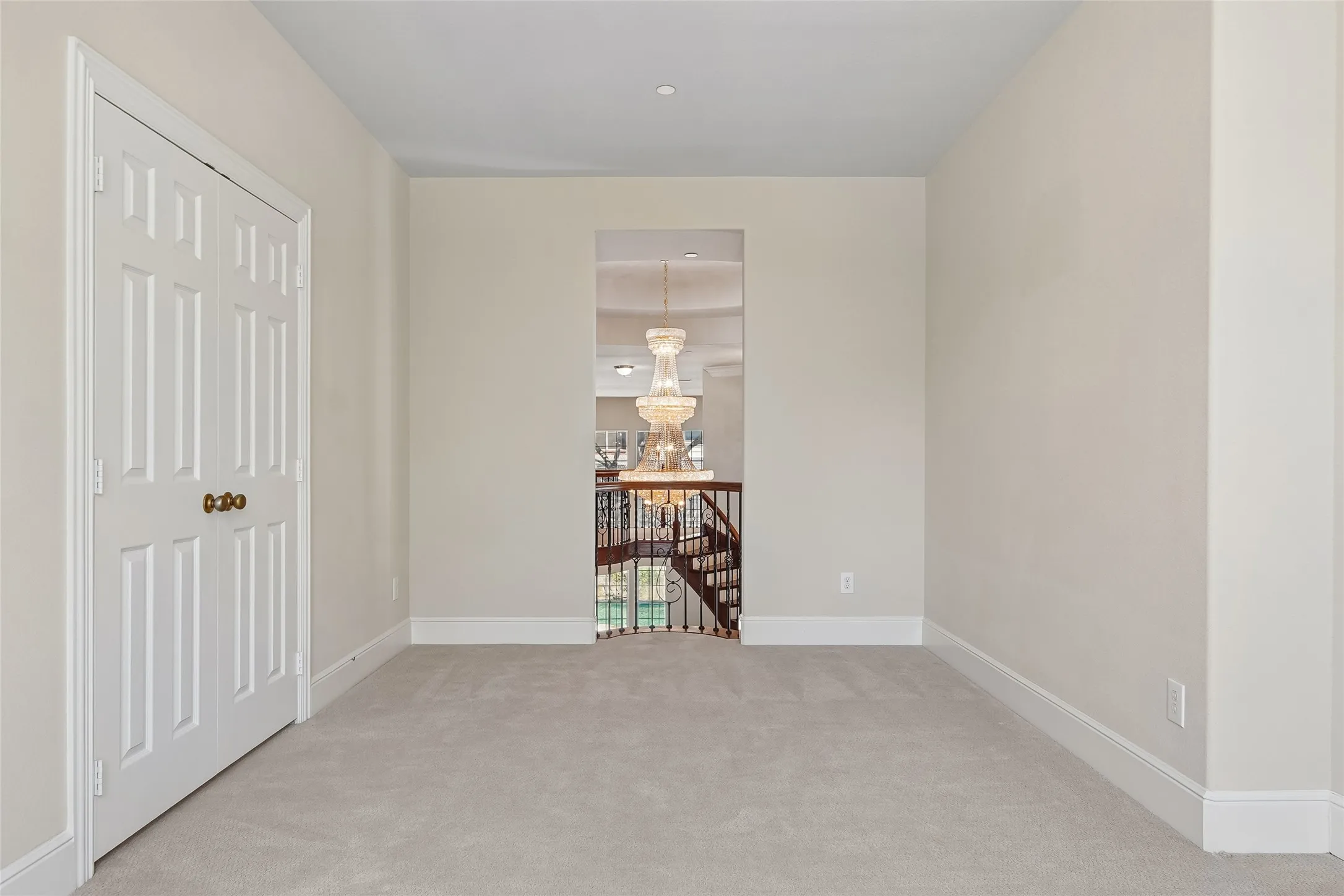Recessed lighting, light neutral wall paint, carpet flooring, base molding, paneled door with brass hardware