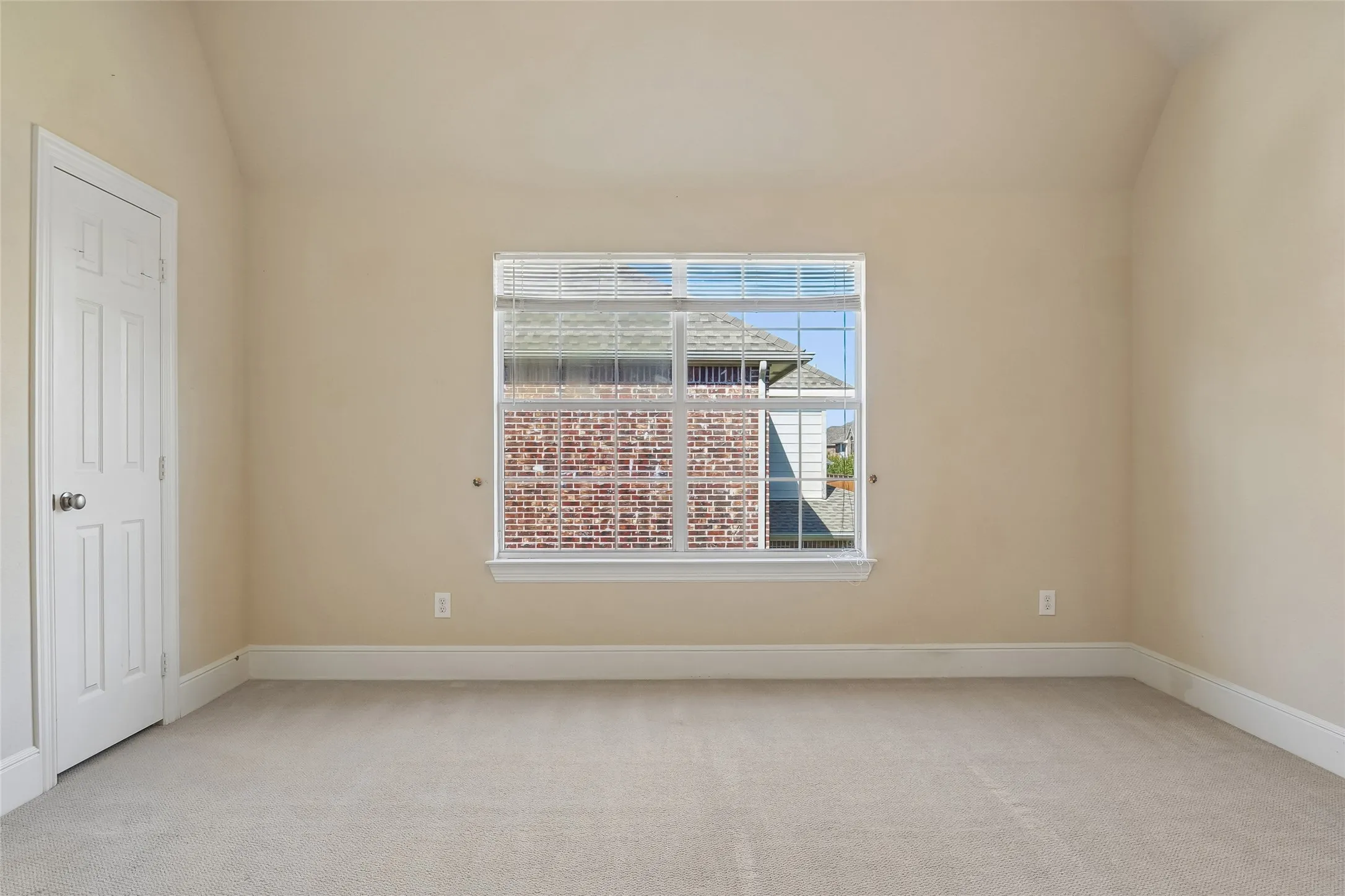 Carpeted room featuring a single window and a paneled door