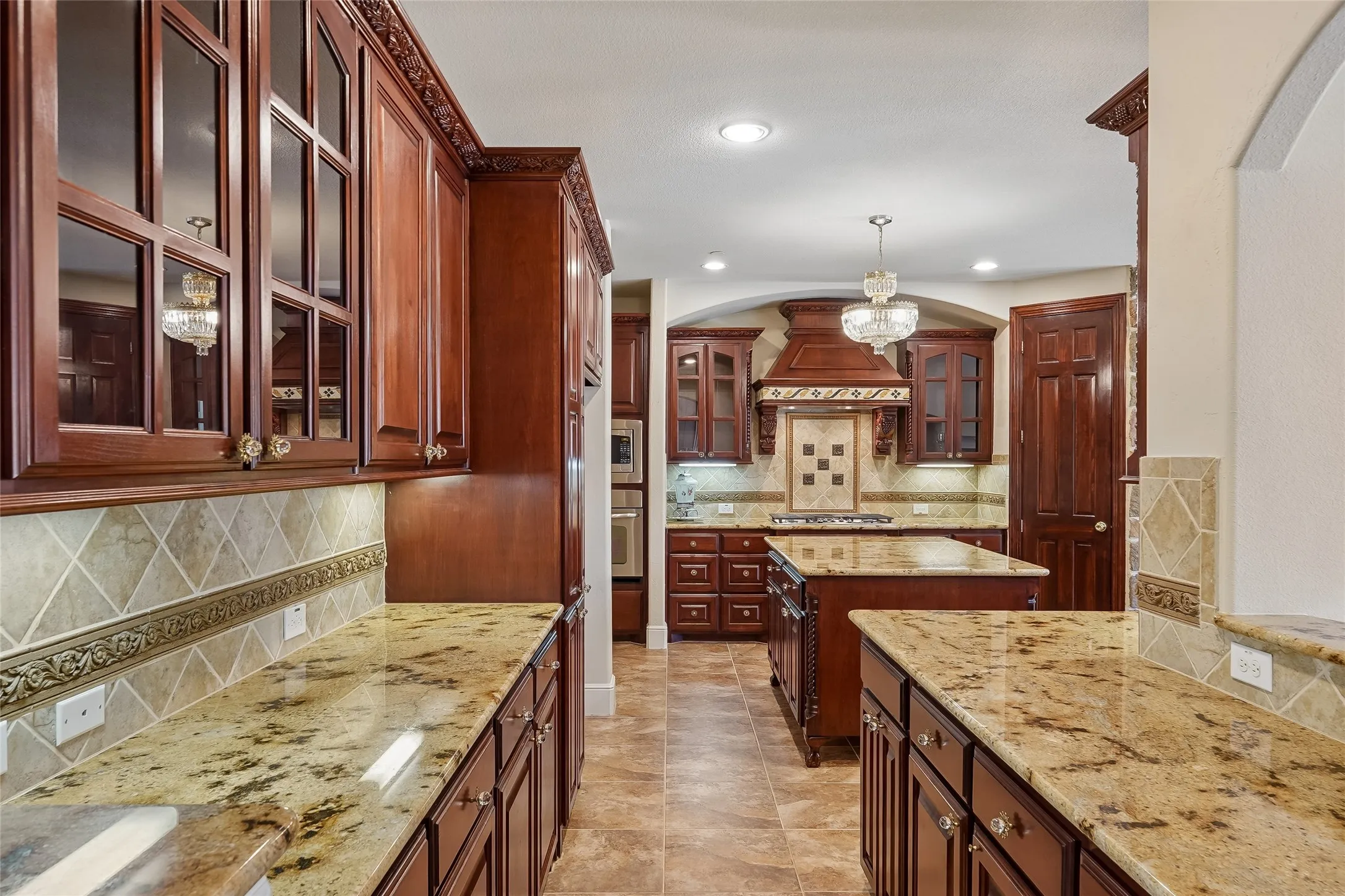 Kitchen featuring wood cabinetry, granite countertops, decorative tile backsplash, and a central island