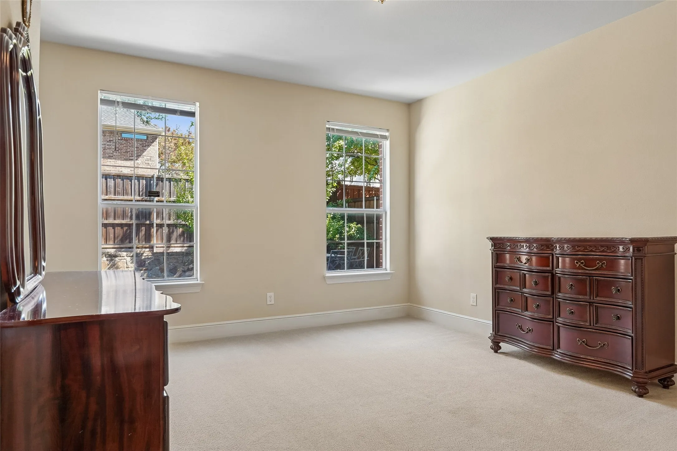 Carpeted room with neutral wall tones and two double-hung windows