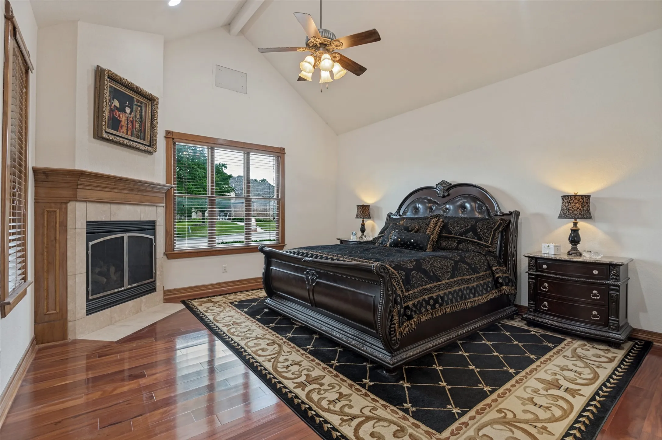 Main-floor primary suite with hardwood floors, a vaulted ceiling, and a corner fireplace
