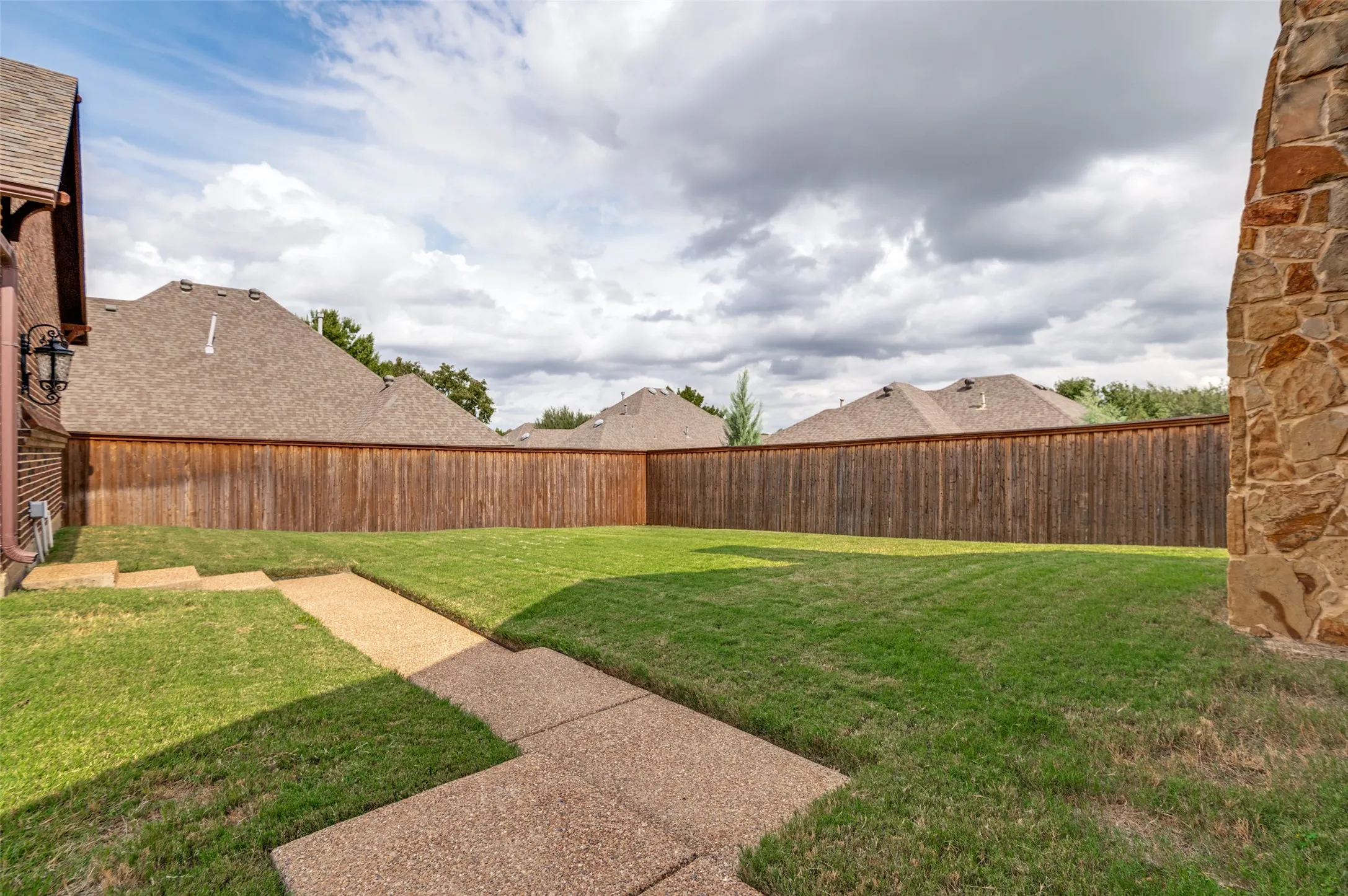 Fenced backyard with a stone walkway and room to play