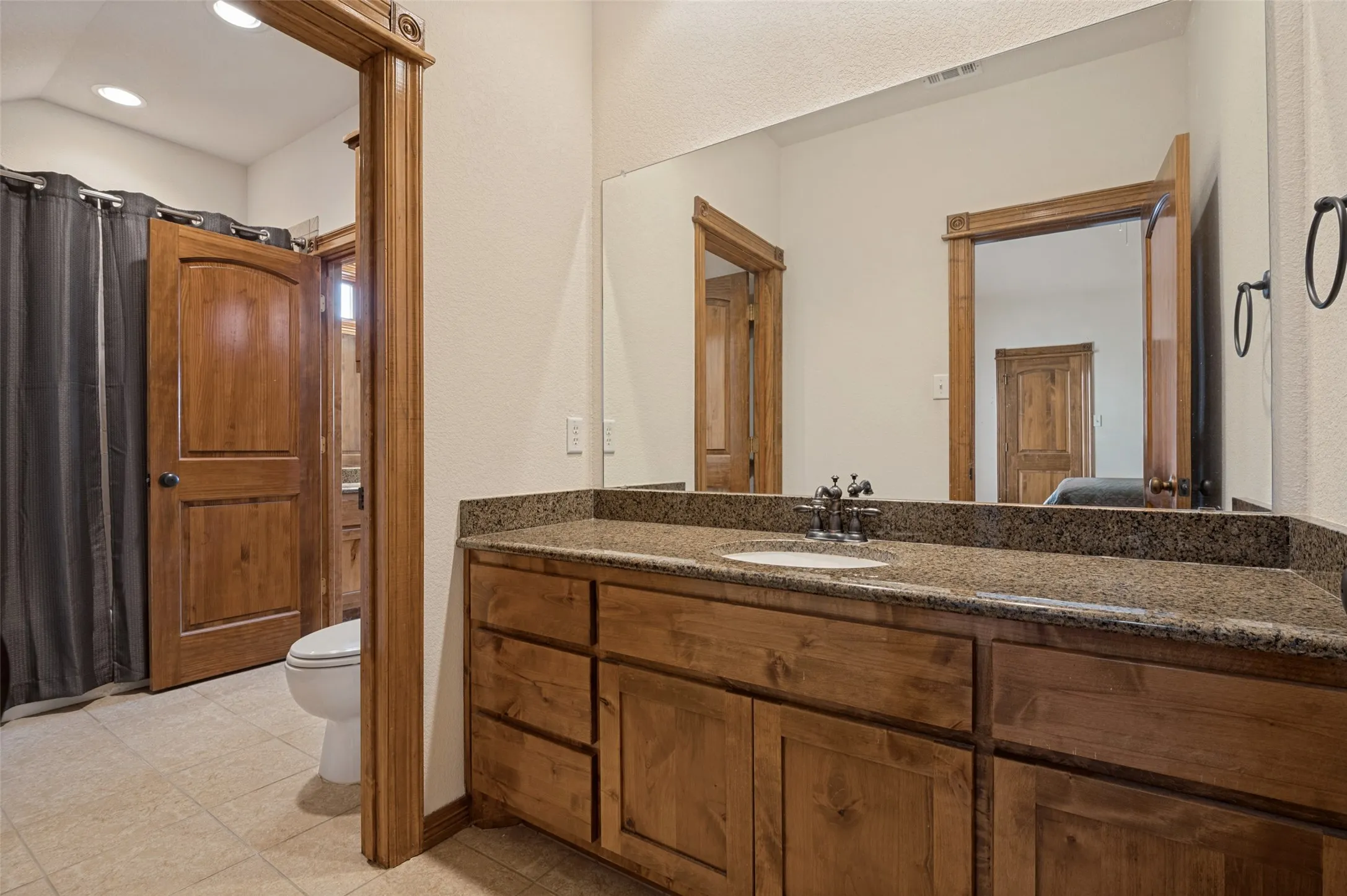 Secondary bath with a granite vanity and walk-in closet access
