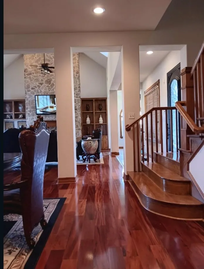 Rich hardwood floors and a curved wood staircase with oen sightlines to the family room