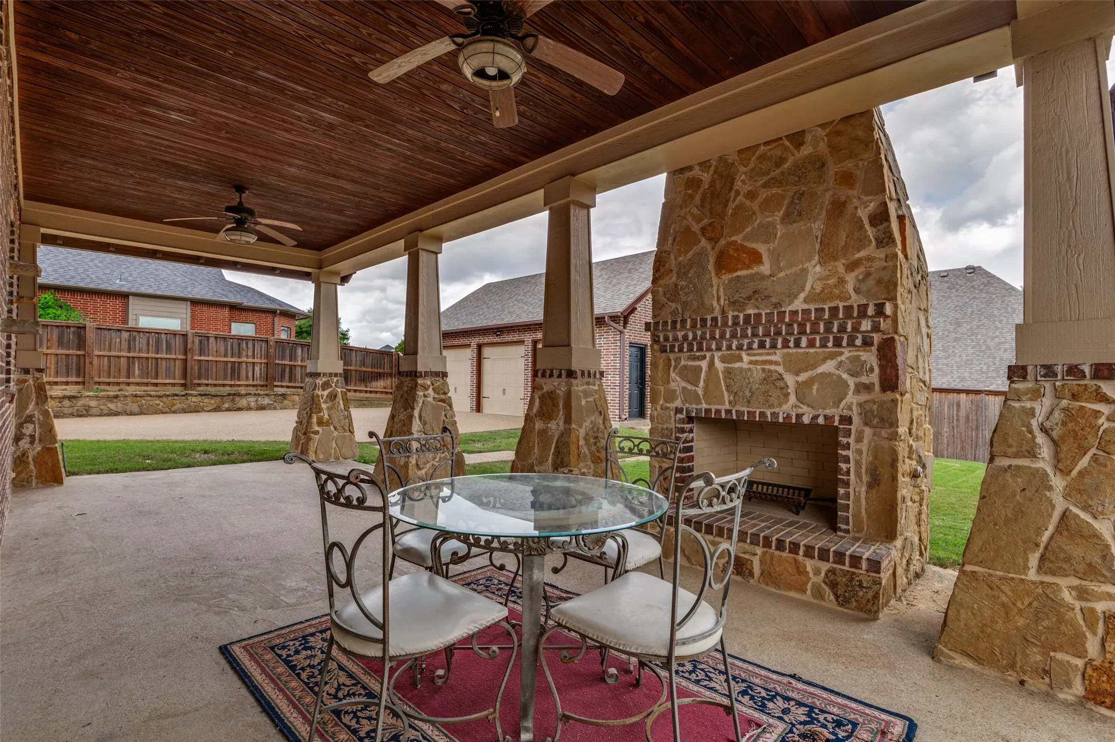 Covered patio with a stone wood-burning fireplace and ceiling fans