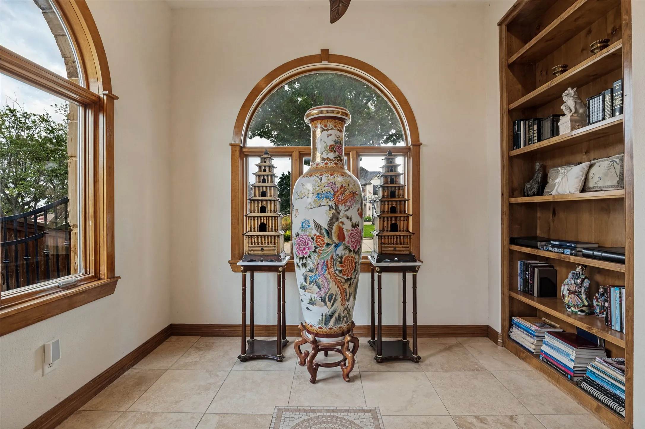 Reading nook with an arched window and floor-to-ceiling built-in bookshelves