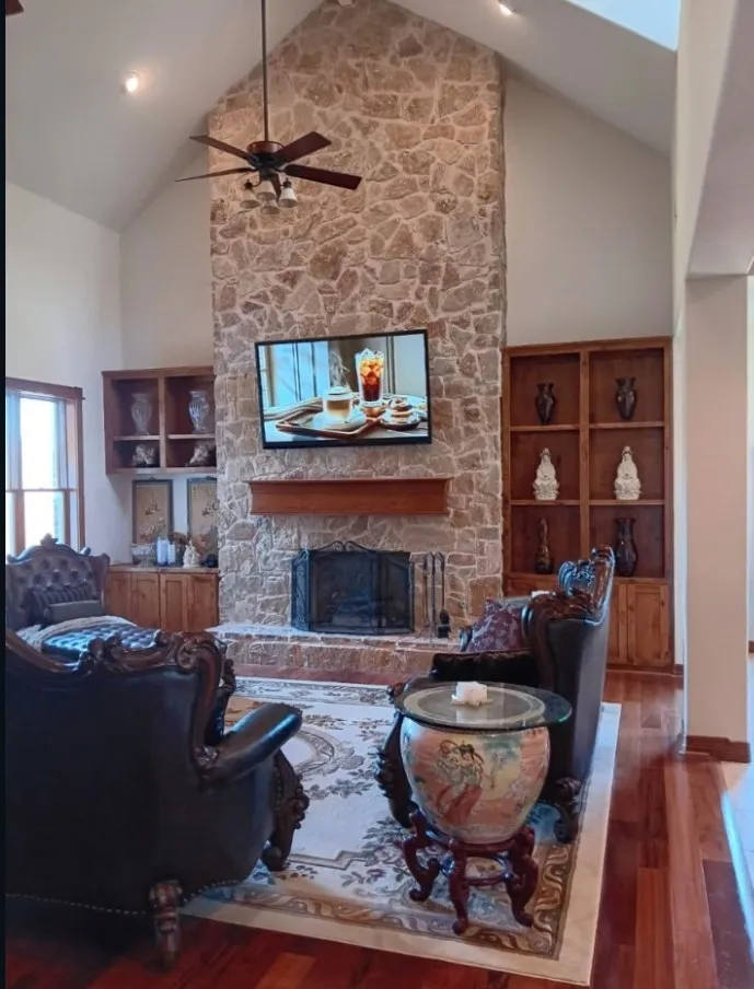 Two-story wood-burning fireplace with a cedar mantel and built-in display shelving