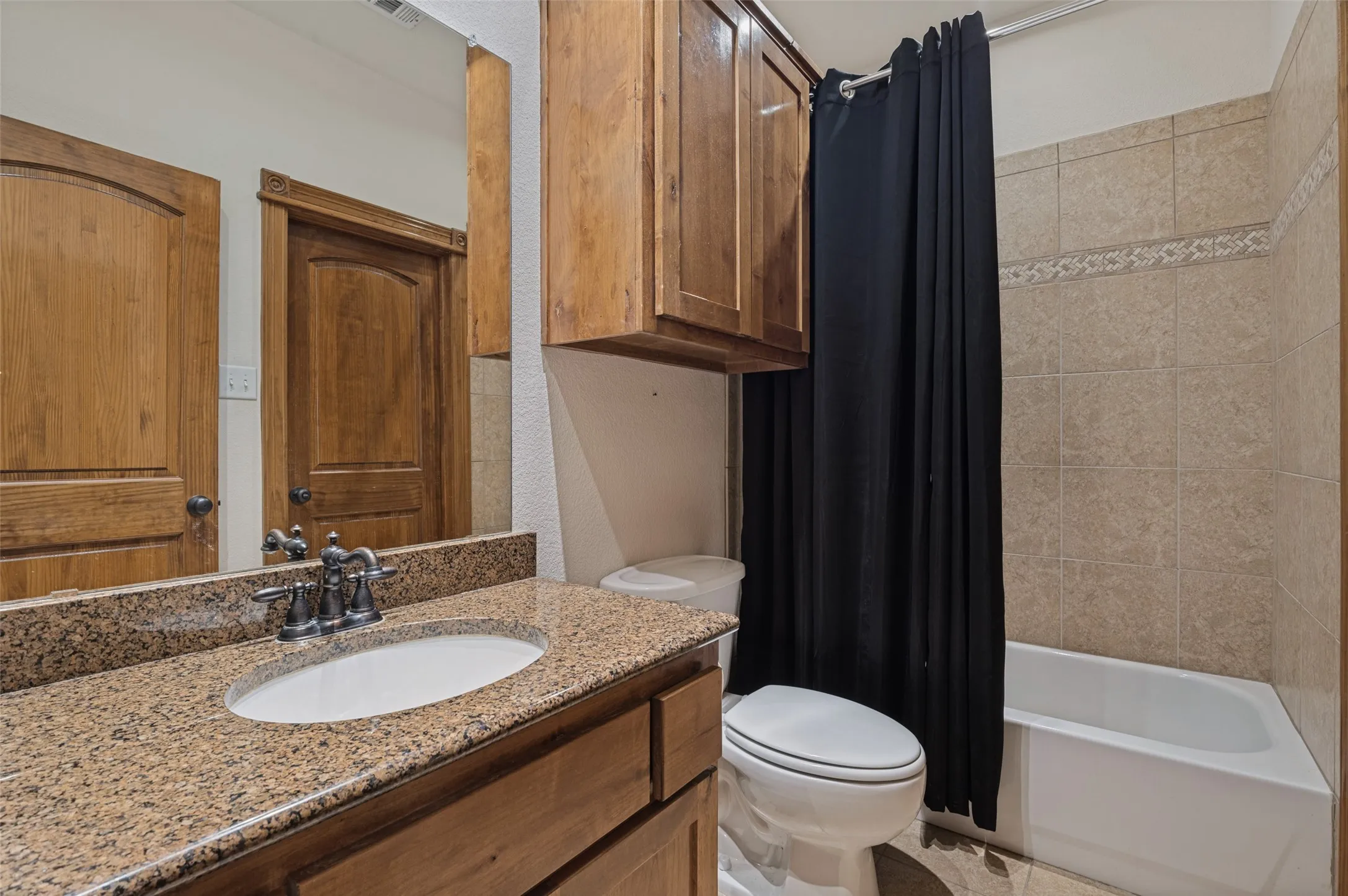 Full bath with a granite vanity and a tub-shower combo