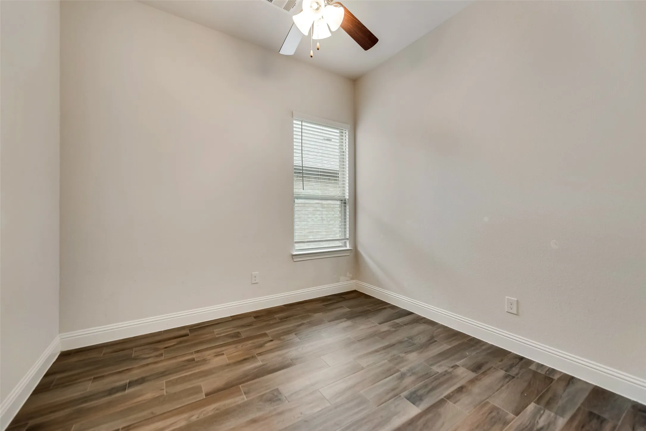 Vaulted ceiling with a ceiling fan, wood-finish flooring, and natural light from the window with blinds