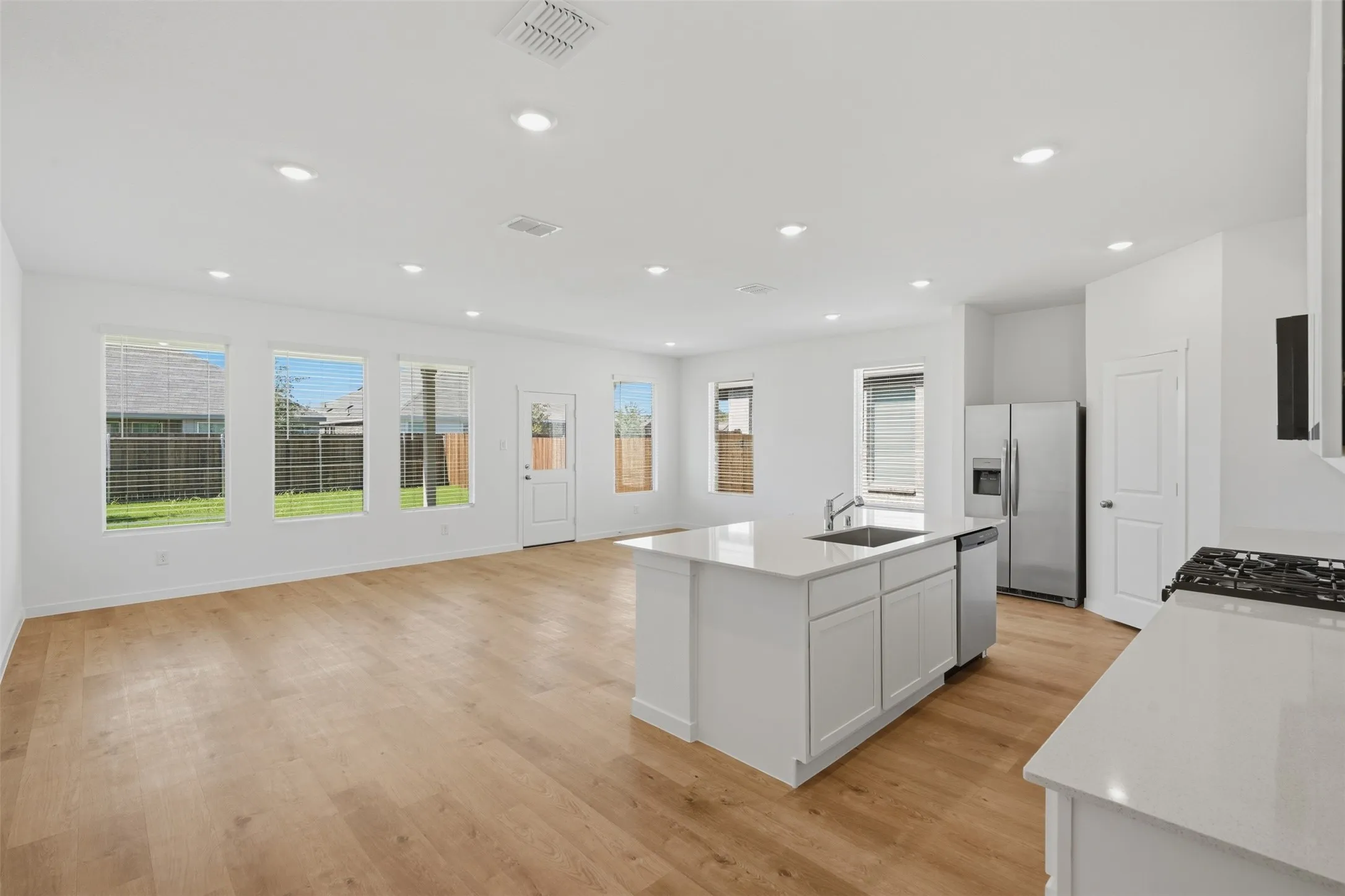 Open-concept living space featuring wood-finish flooring, recessed lighting, and multiple windows
