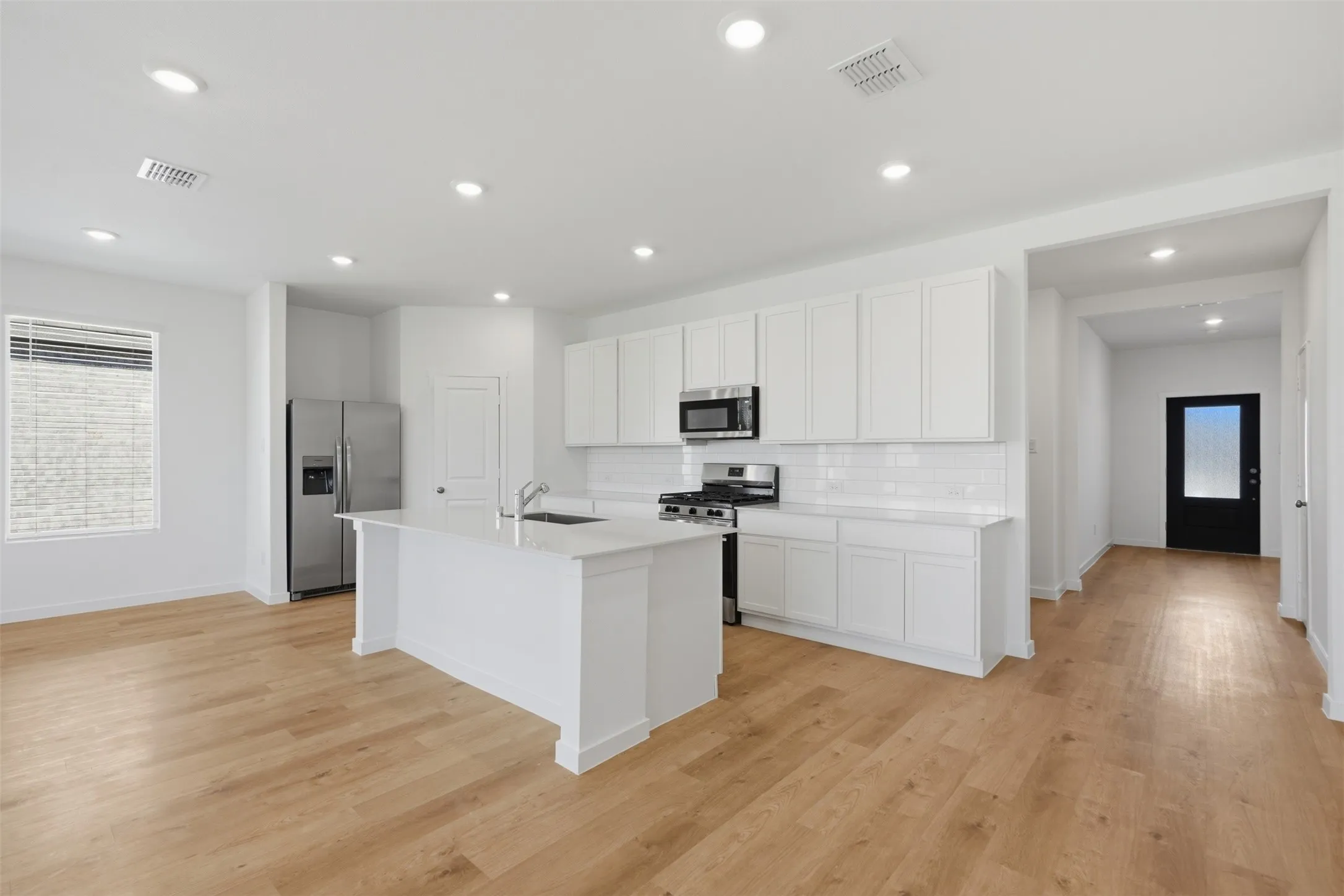 Open-concept layout featuring wood-finish flooring, recessed lighting, and white cabinetry