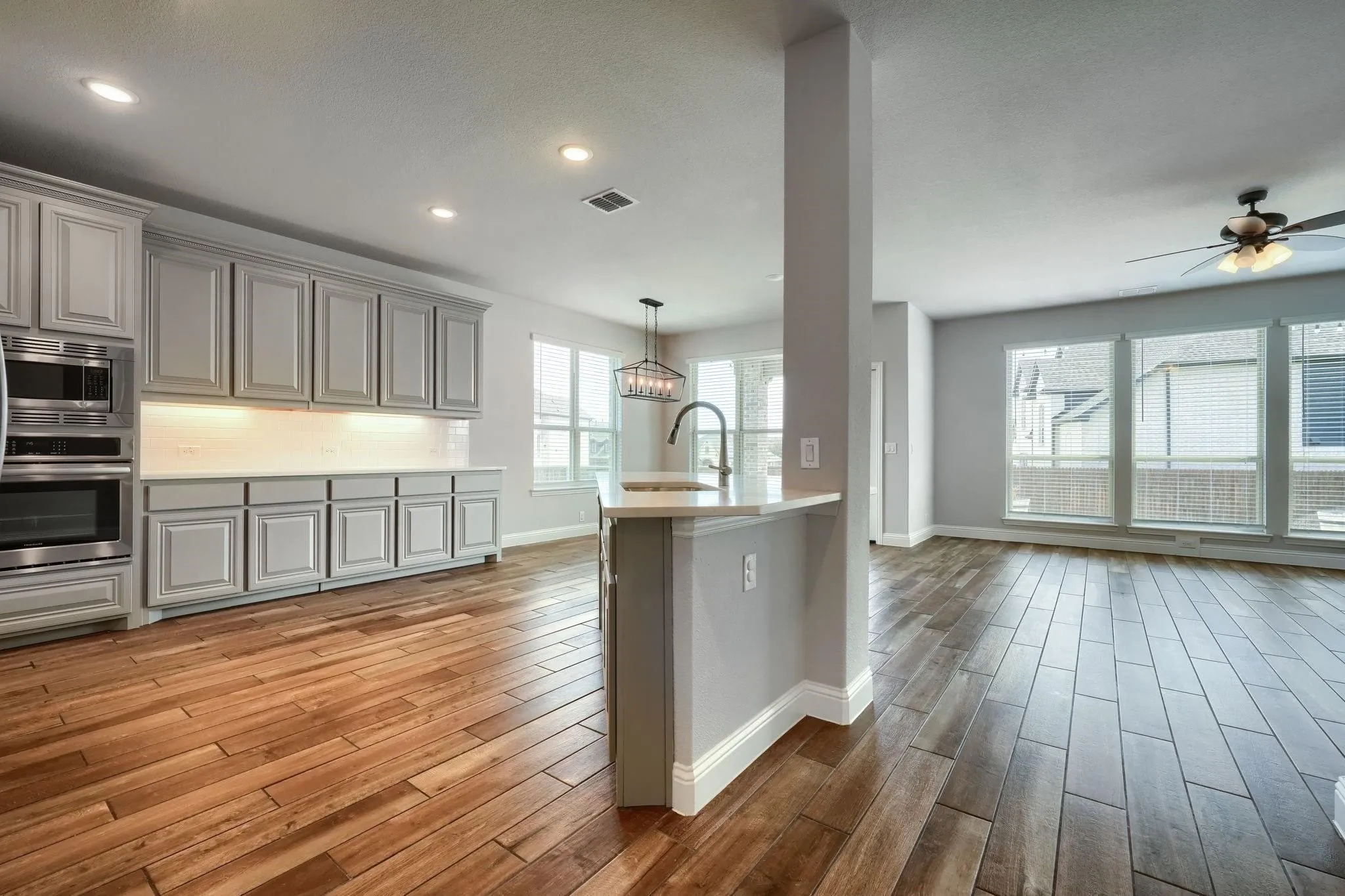 Expansive room with wood-finish flooring, recessed lighting, and a ceiling fan