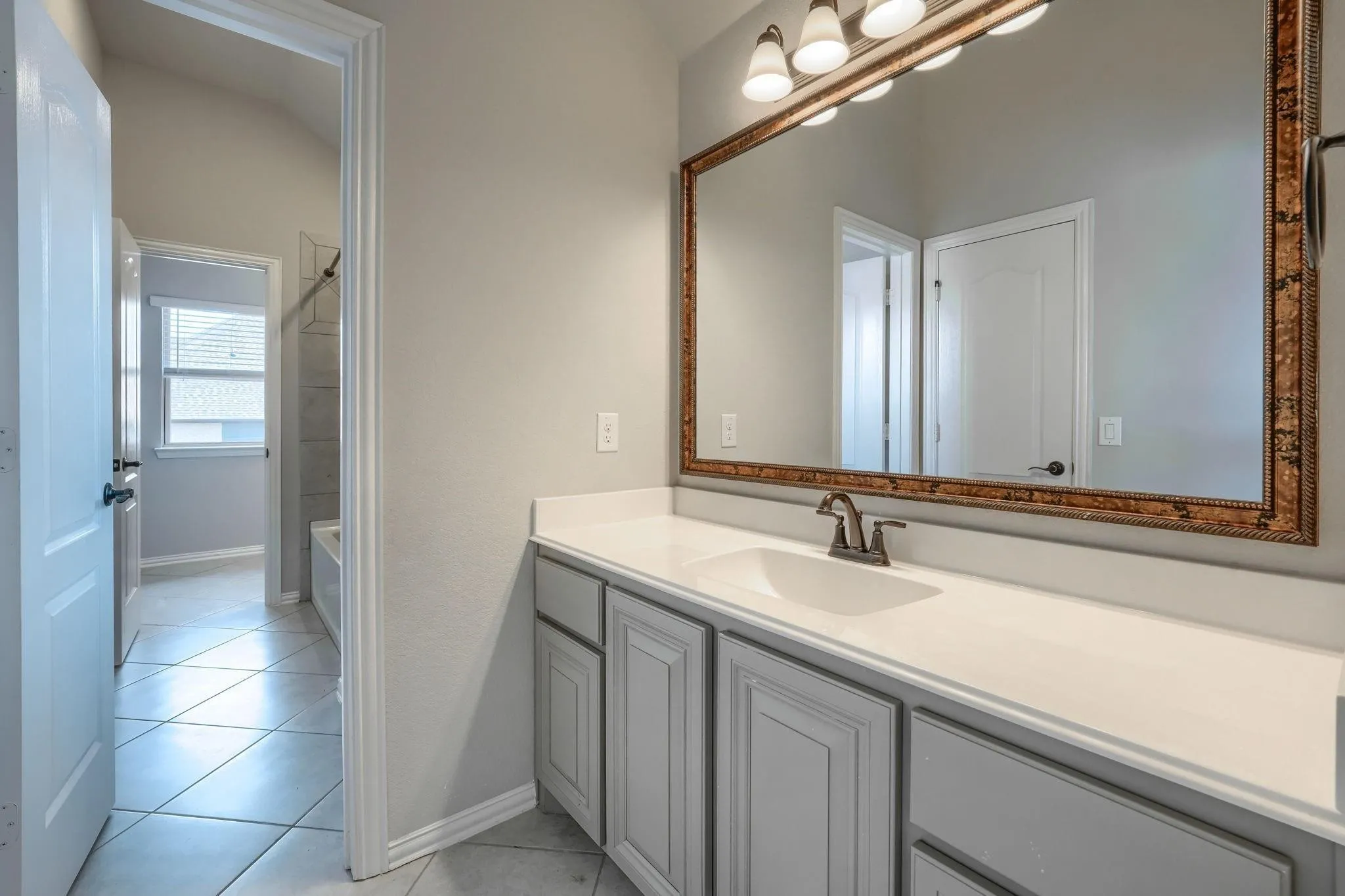 White single vanity with gray cabinetry, white countertop, rectangular inset sink, and bronze-finish faucet
