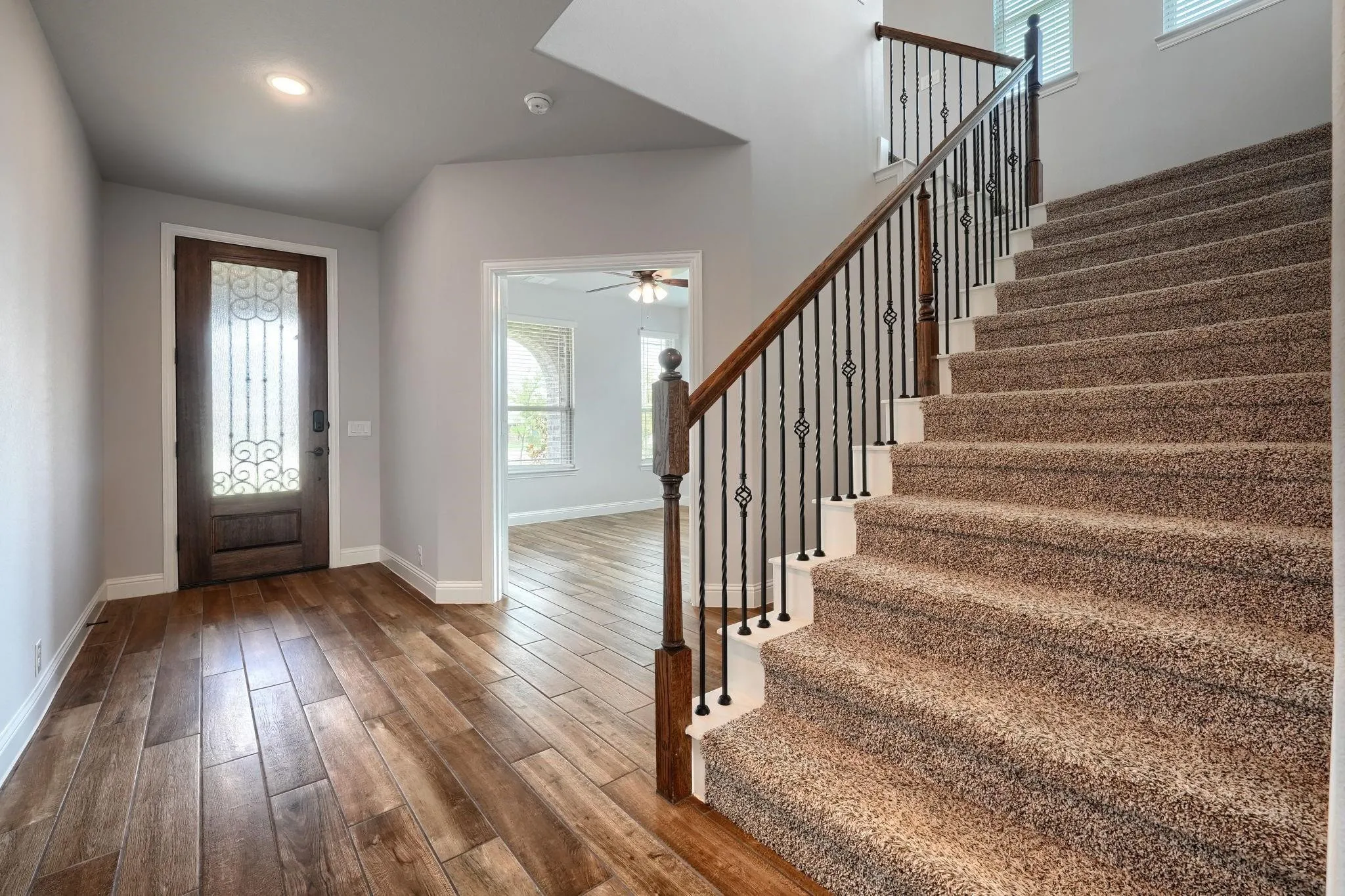 Entryway featuring wood-finish flooring, decorative glass paneled door, recessed lighting, and a staircase with wrought iron balusters and wood handrail