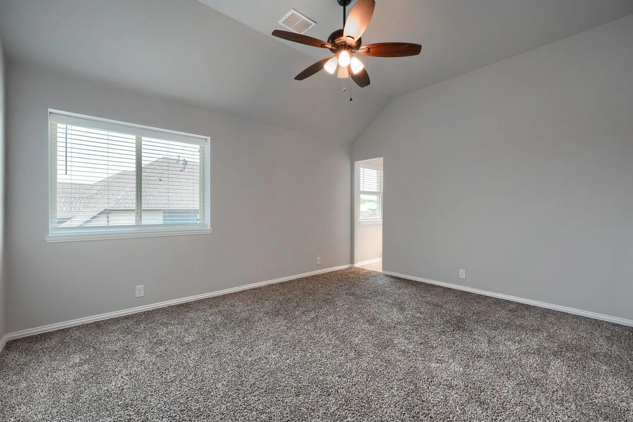 Vaulted ceiling with an attached ceiling fan, neutral wall paint, light-colored carpeting, and a window with blinds