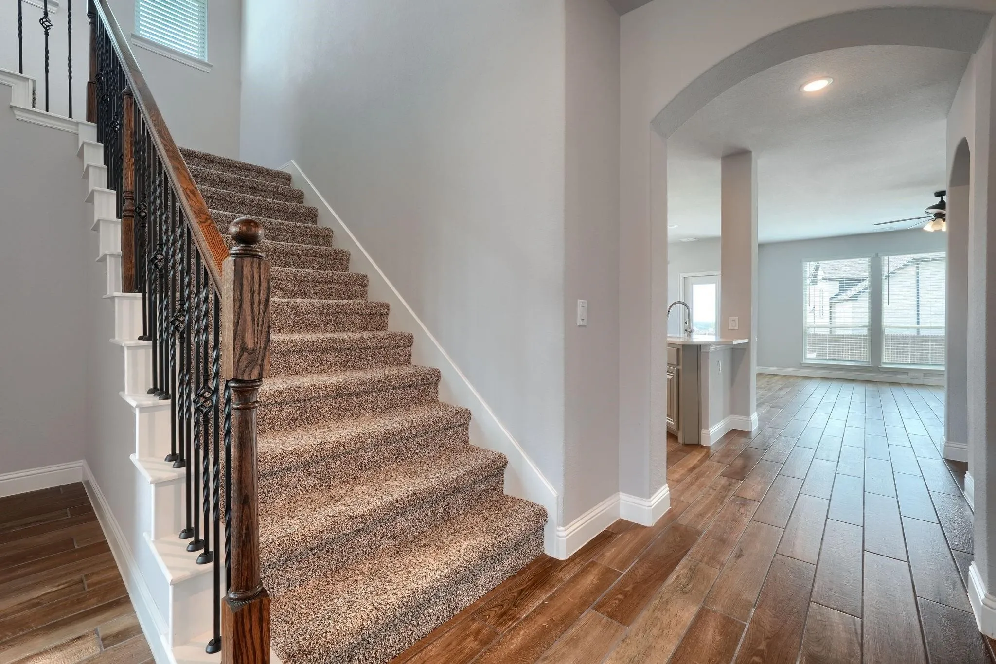 Carpeted staircase with wrought iron balusters and wood-finish handrail
