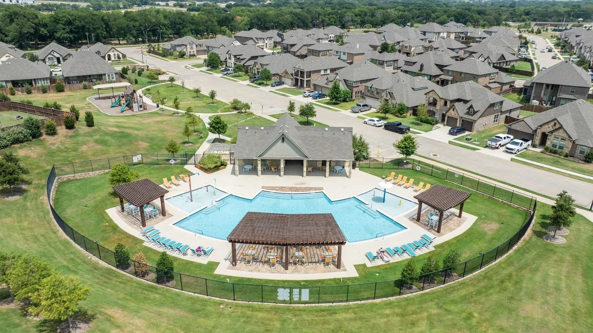 Community swimming pool with an adjacent covered pavilion, surrounding hardscaping, and nearby playground