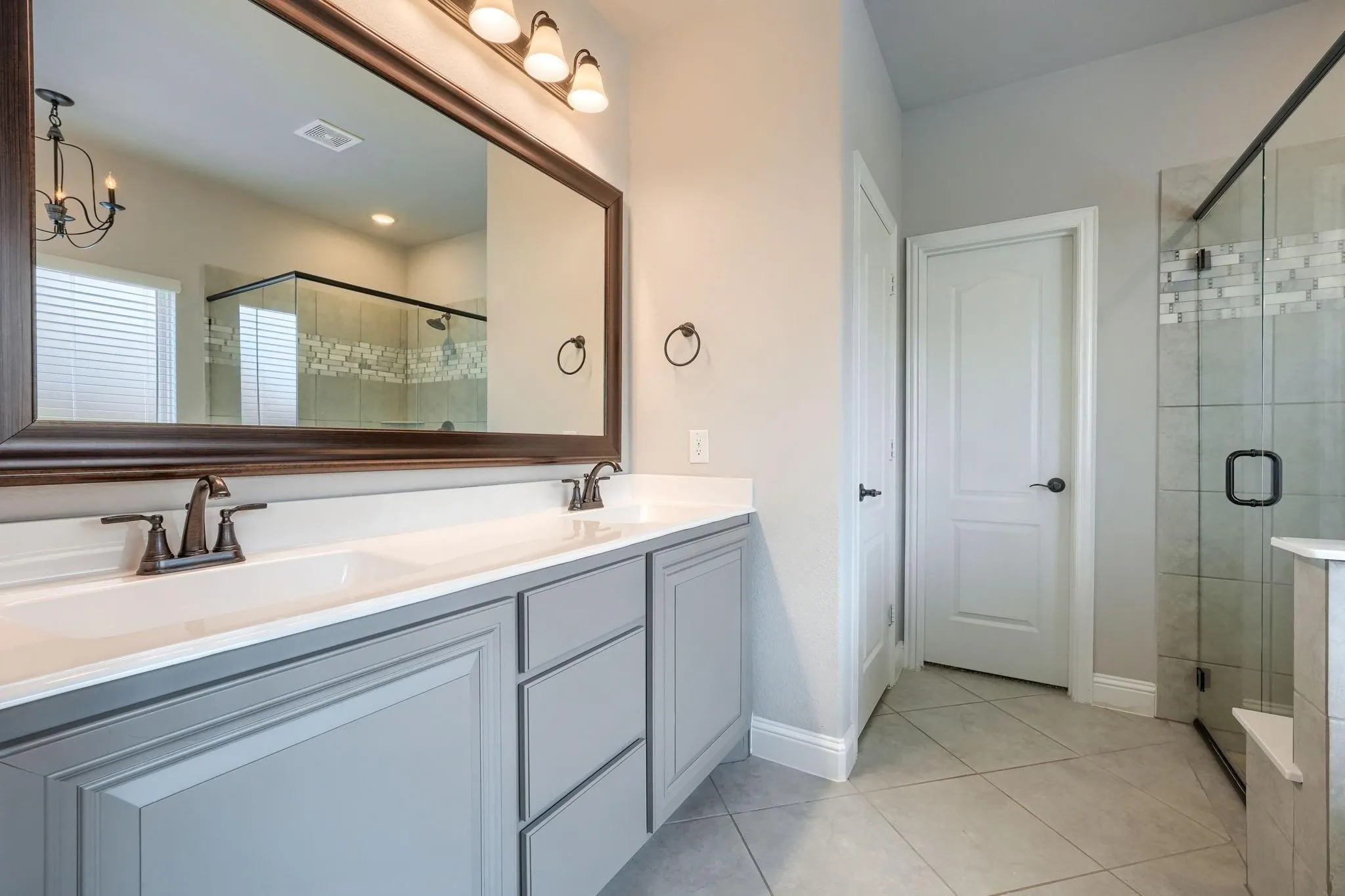 Dual vanity with gray cabinetry, white countertops, and bronze-finish faucets
