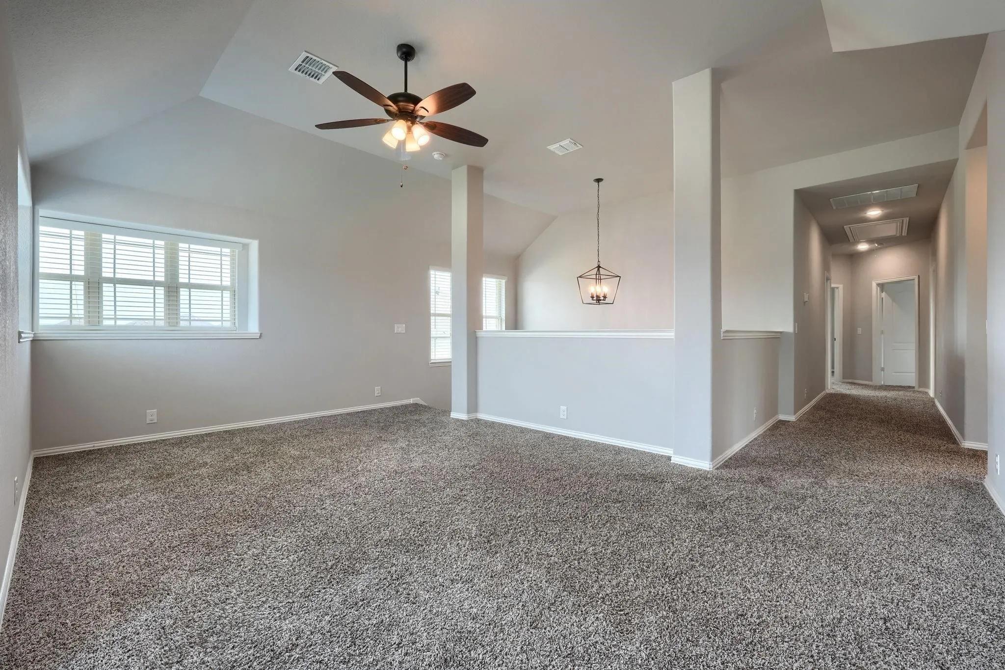 Vaulted ceiling, ceiling fan, carpet flooring, multiple windows, pendant light fixture