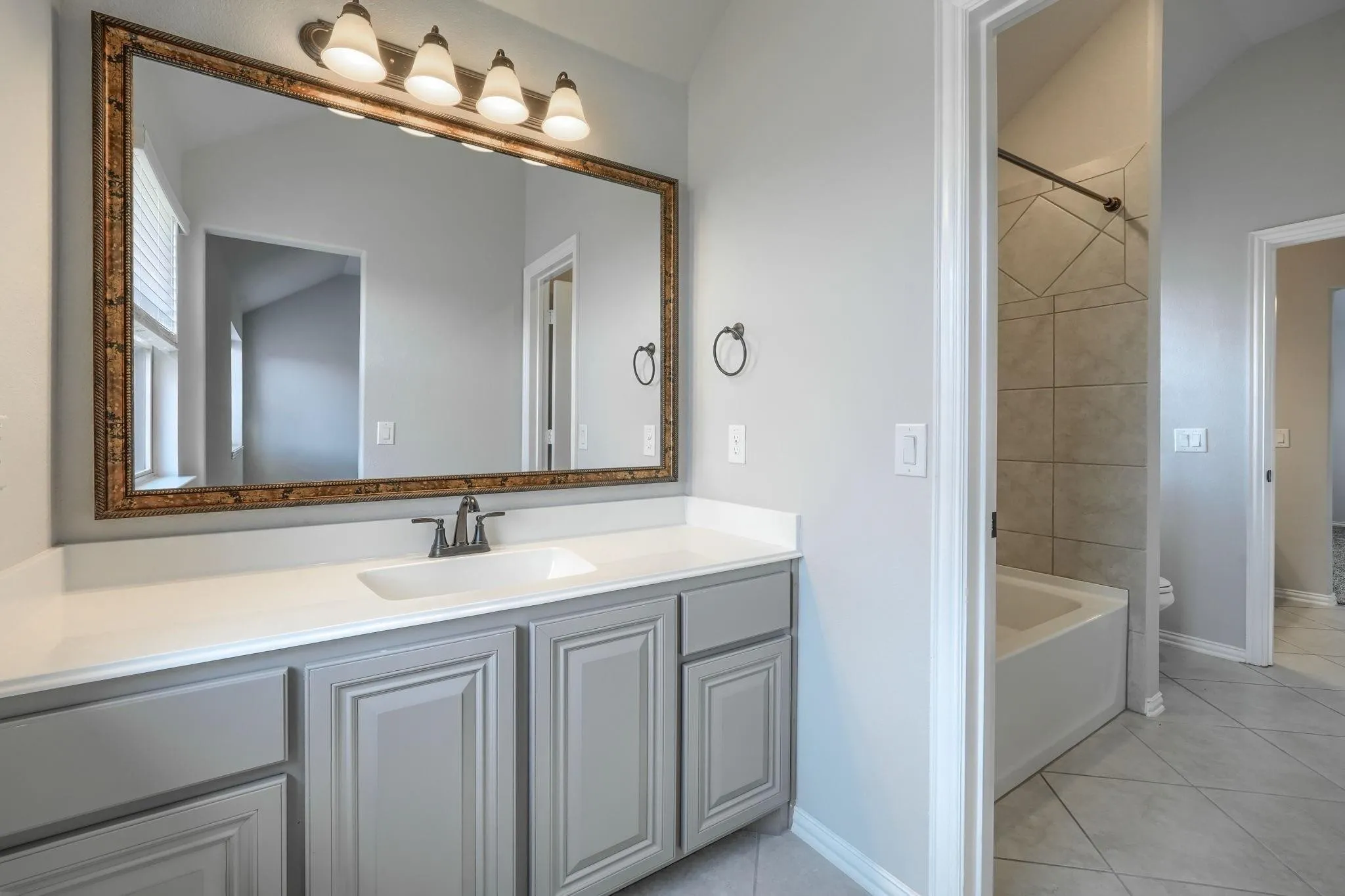 Vanity with a single basin sink, white countertop, and gray cabinetry