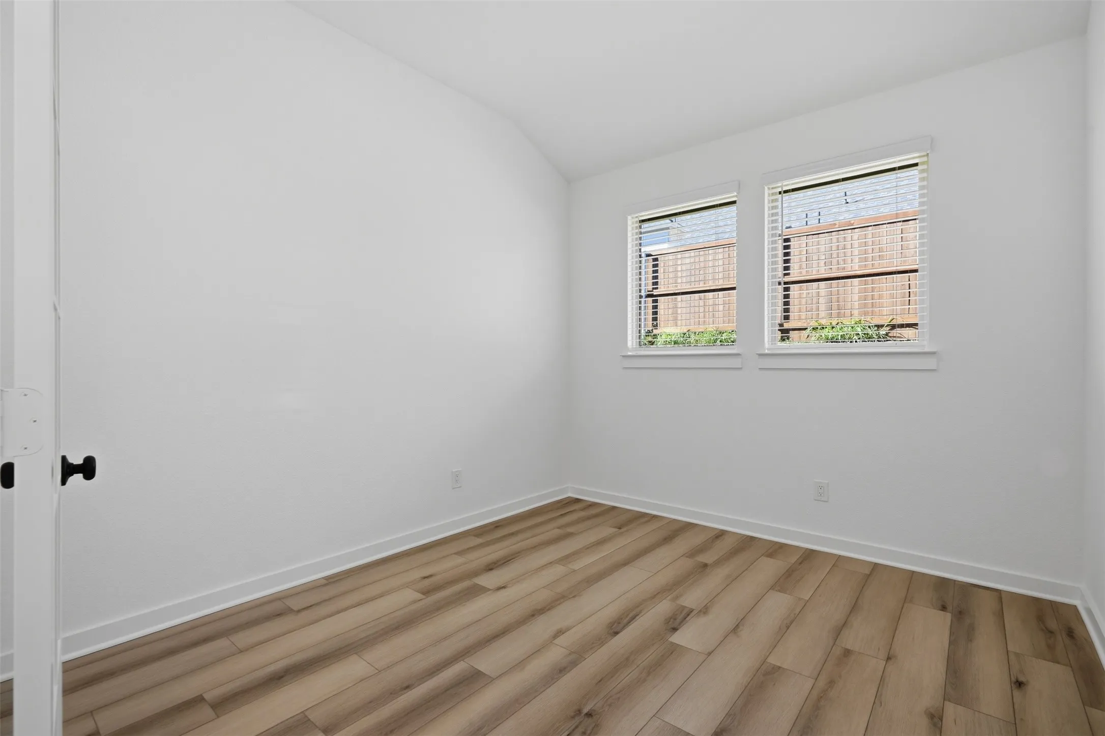 Wood-finish flooring, white walls, and two windows with blinds