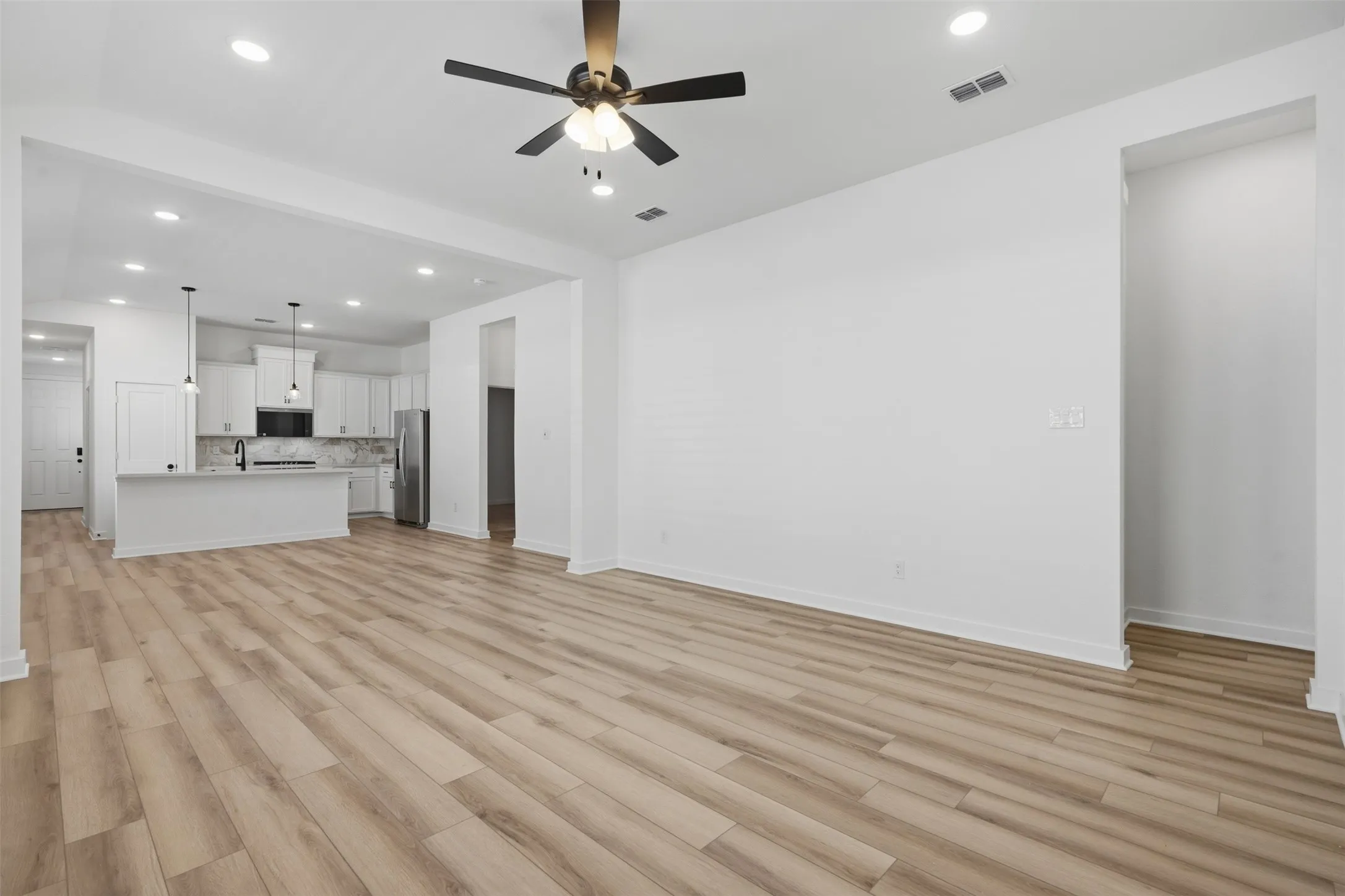Spacious living area featuring wood-finish flooring, recessed lighting, and a ceiling fan