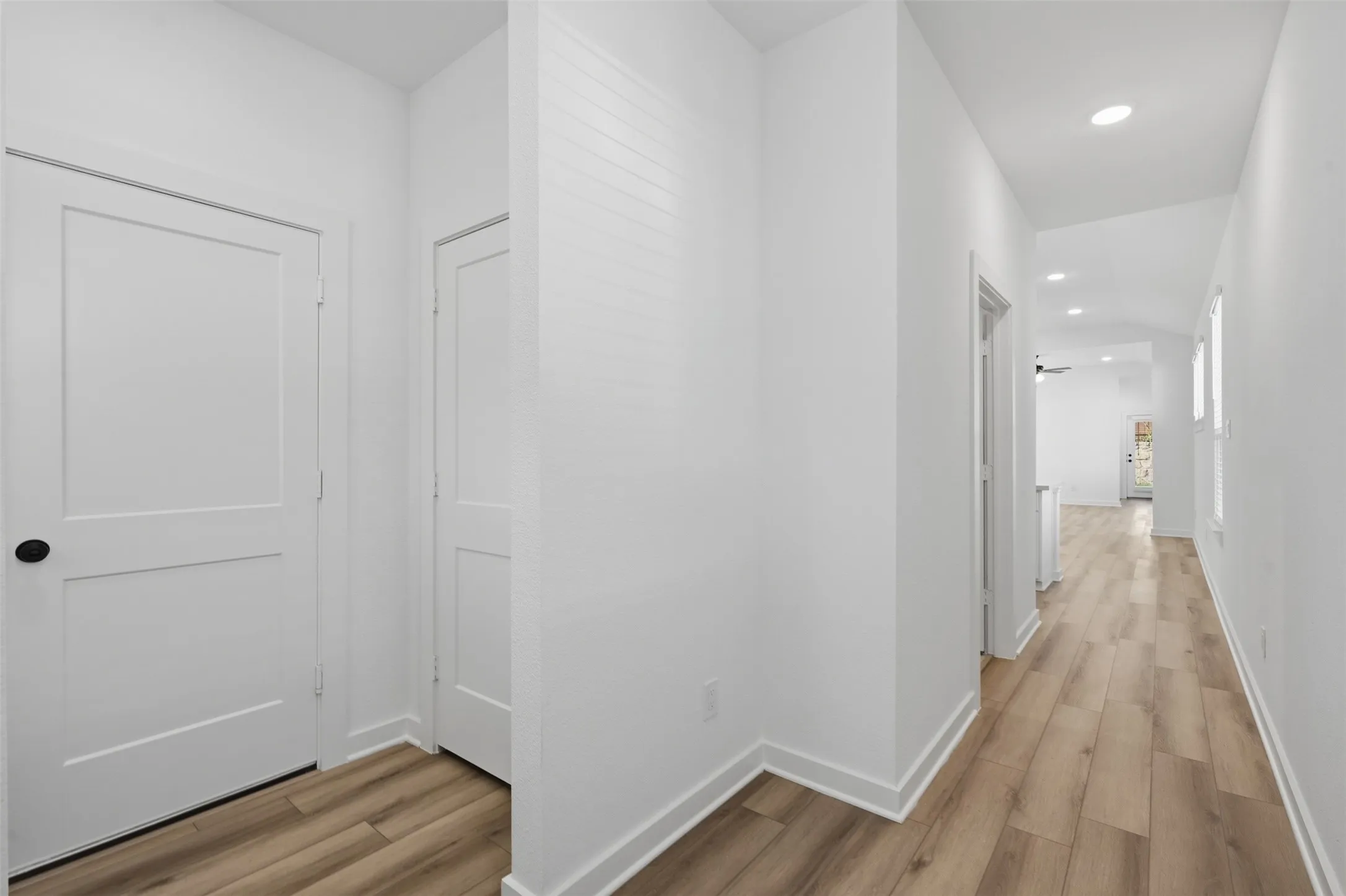White interior walls, recessed ceiling lighting, wood-finish flooring, and white trim