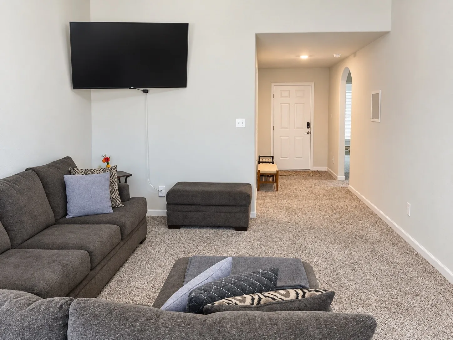 Light-colored wall paint throughout, vaulted ceiling, arched doorway, and light-colored carpet