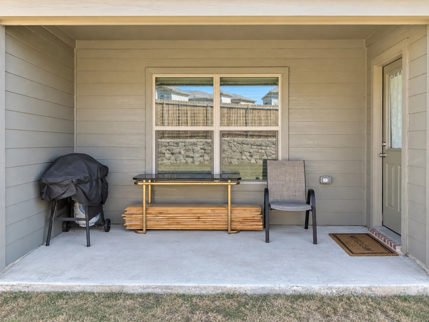 Expansive yard area featuring a wooden privacy fence, stone retaining wall, and a gate