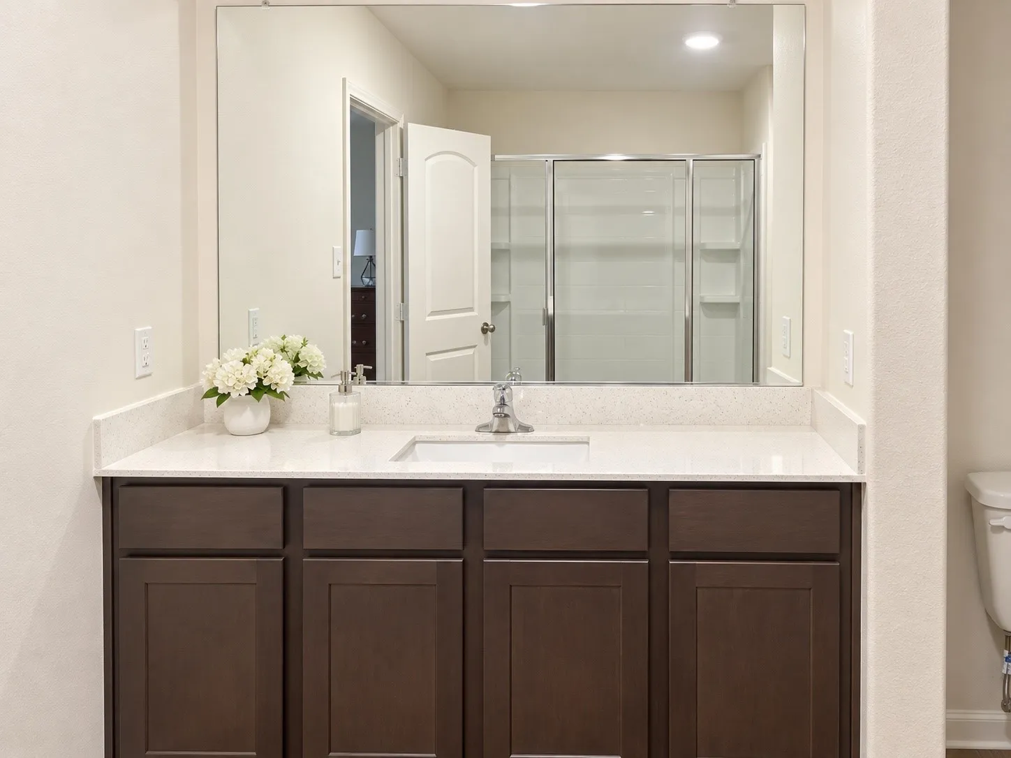 Vanity with a white countertop and integrated sink, chrome faucet, and dark wood-finish cabinetry