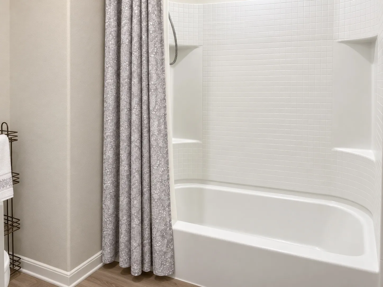White tile shower surround with integrated shelving and a white soaking tub