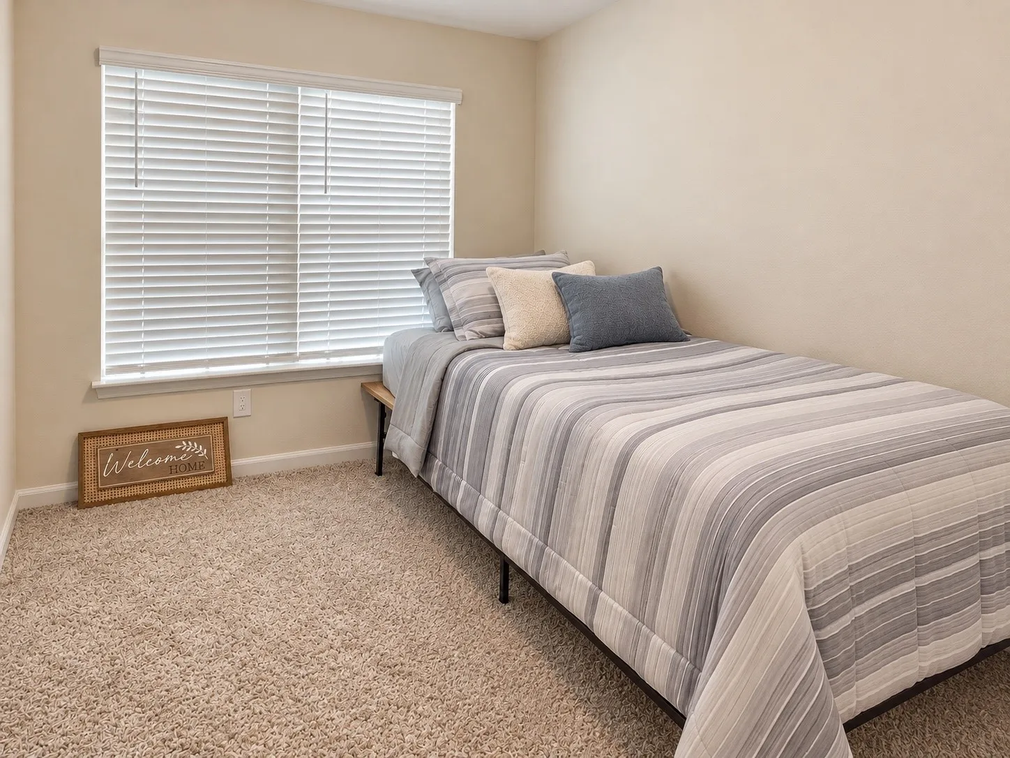 Textured carpeting and a large window with white blinds