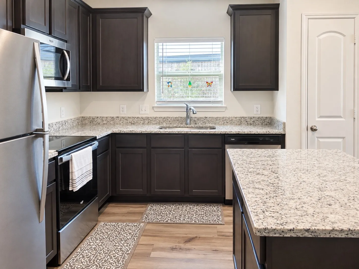 Kitchen featuring dark wood-finish cabinetry, light-toned granite countertops, and stainless steel appliances