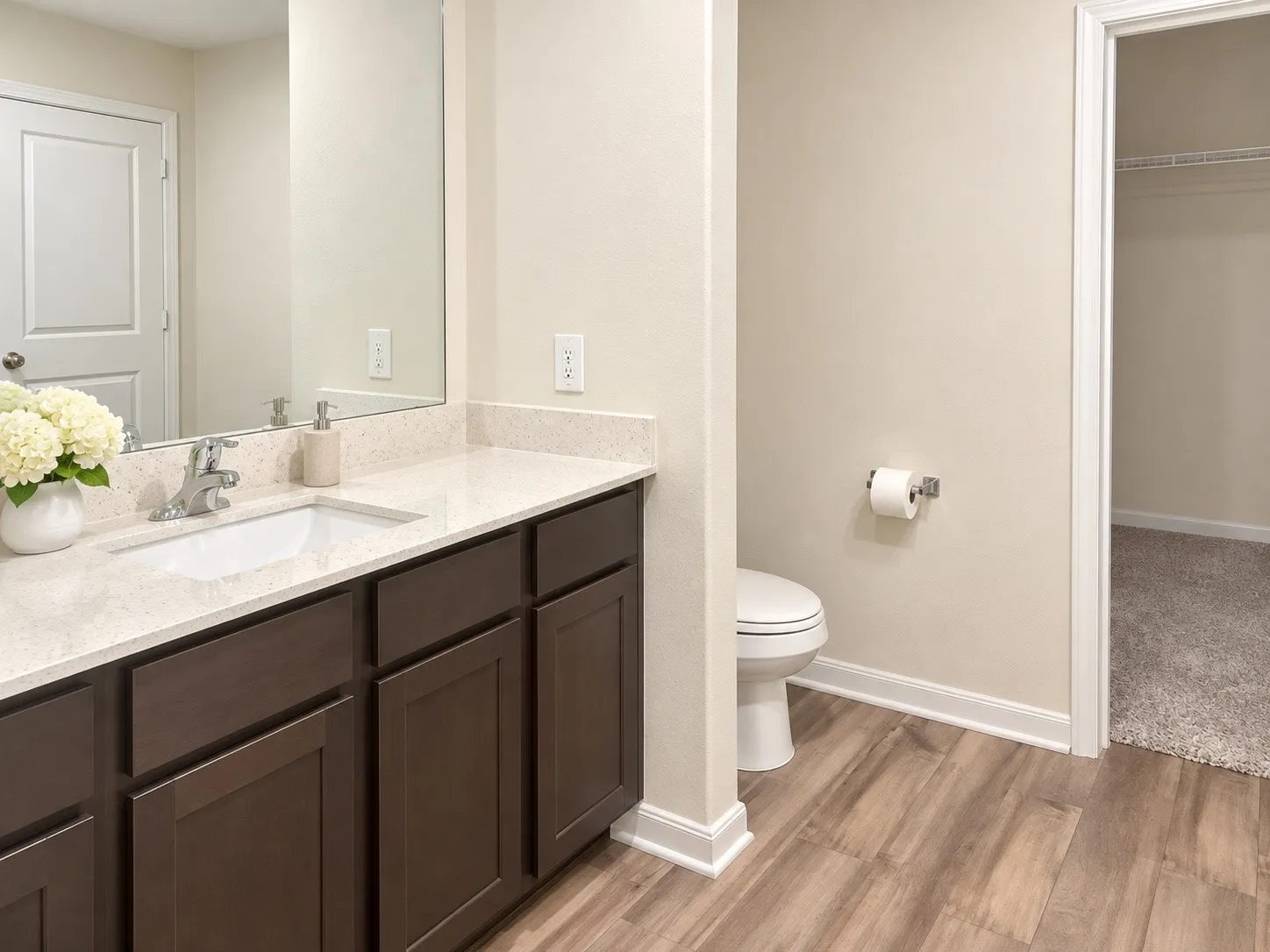 Vanity with an integrated rectangular sink, stone-finish countertop, dark wood-finish cabinetry, and wood-finish flooring