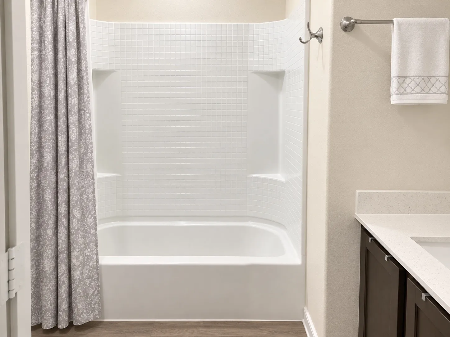White subway tile surround, built-in tub, dual shower shelves, dark wood-finish vanity, light-toned countertop