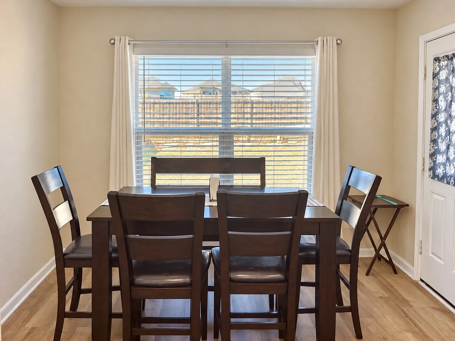 Recessed window with horizontal blinds and drapery rods, light-toned walls, and wood-finish flooring