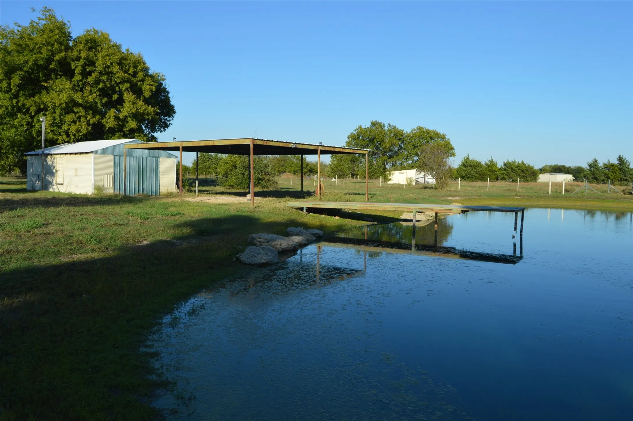 Looking at garage/shop, carport and pond with dock