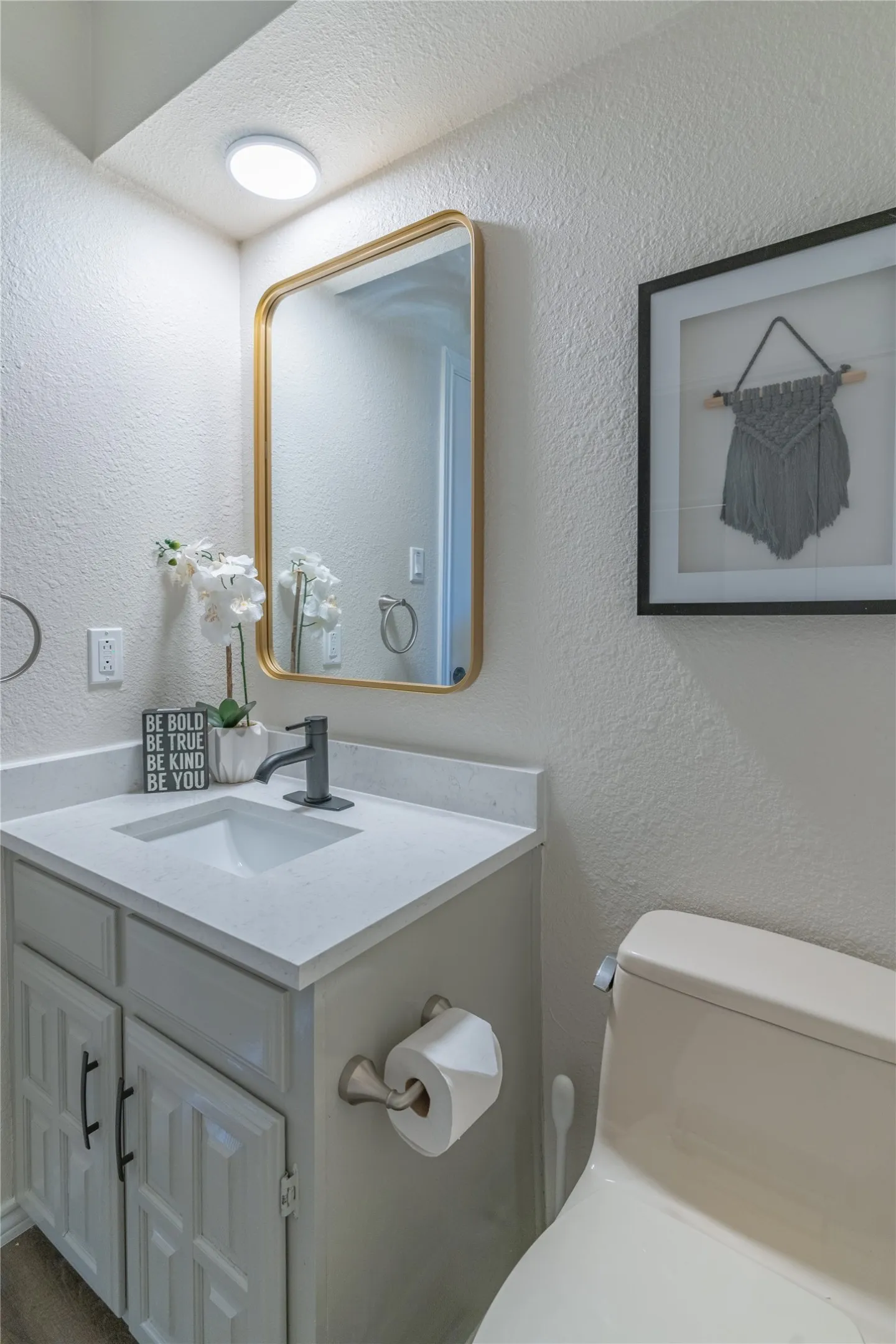 Vanity with a light-toned countertop, matte black faucet, and white cabinetry with black hardware