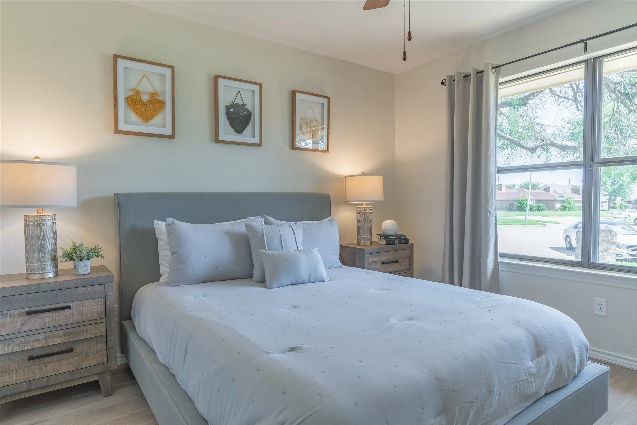 Recessed window with natural light, wood-finish flooring, ceiling fan, and upholstered bed frame
