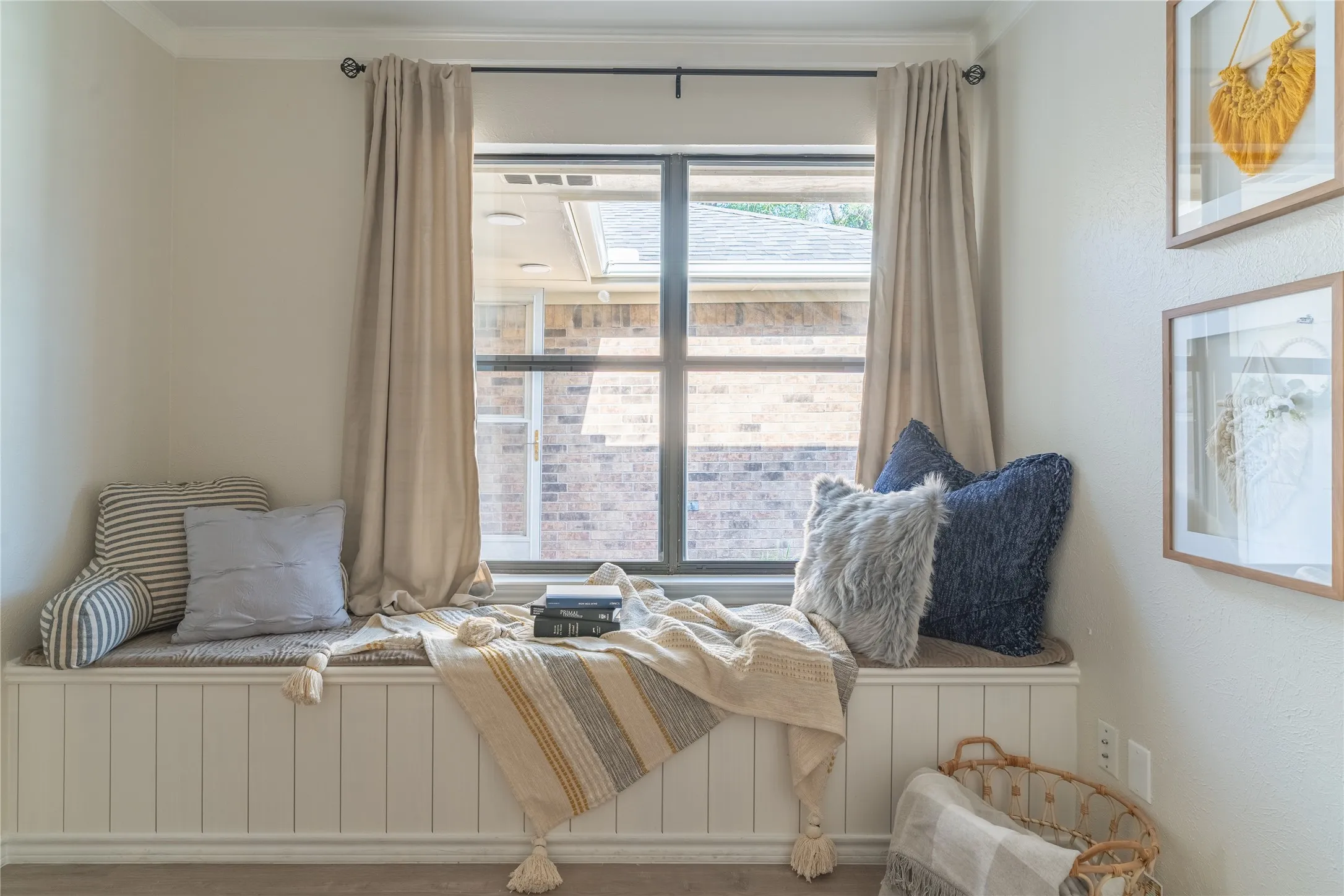 Built-in window seat with vertical paneling, crown molding, and window with dark trim