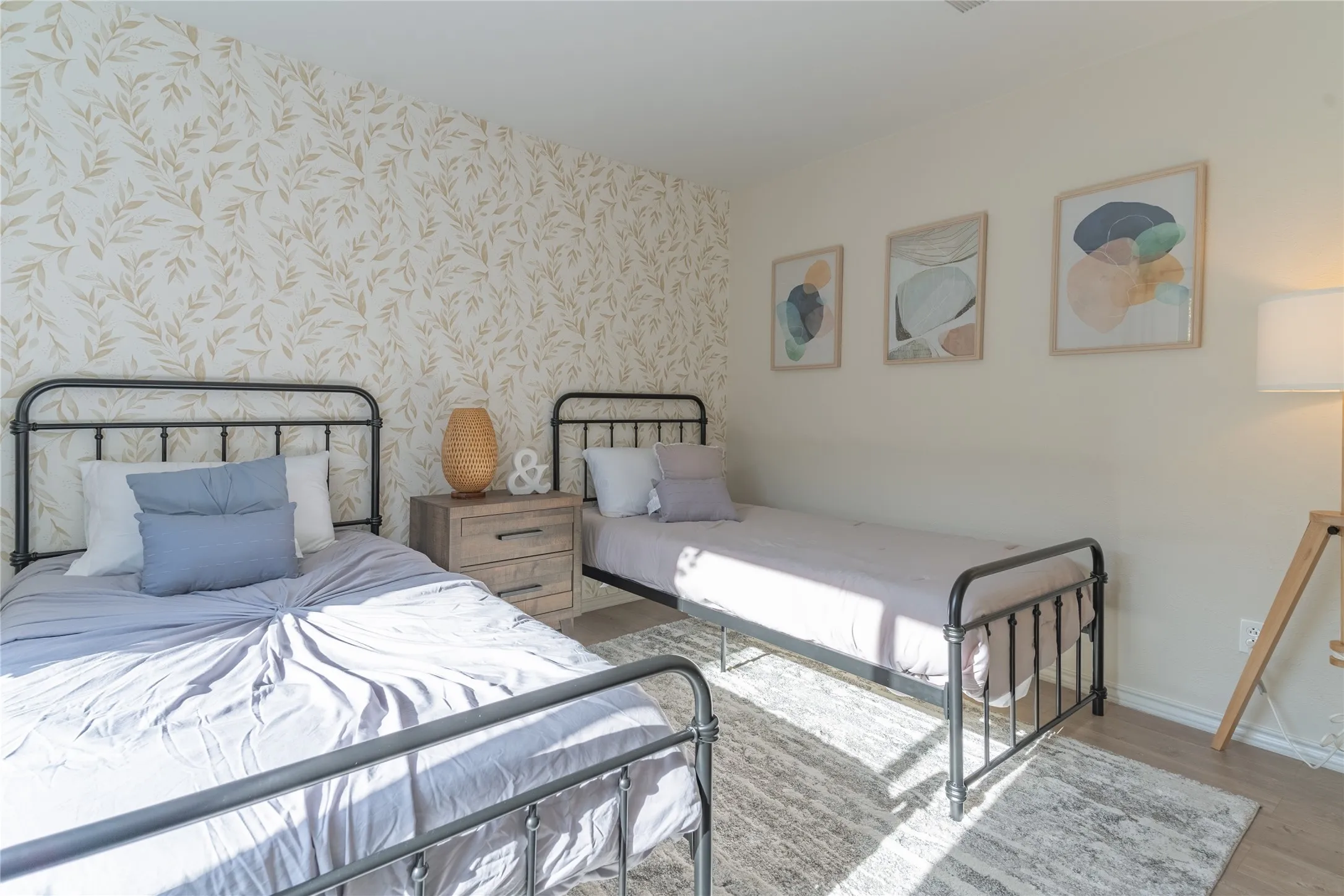 Accent wall with a botanical pattern, light wood-finish flooring, and a neutral wall color