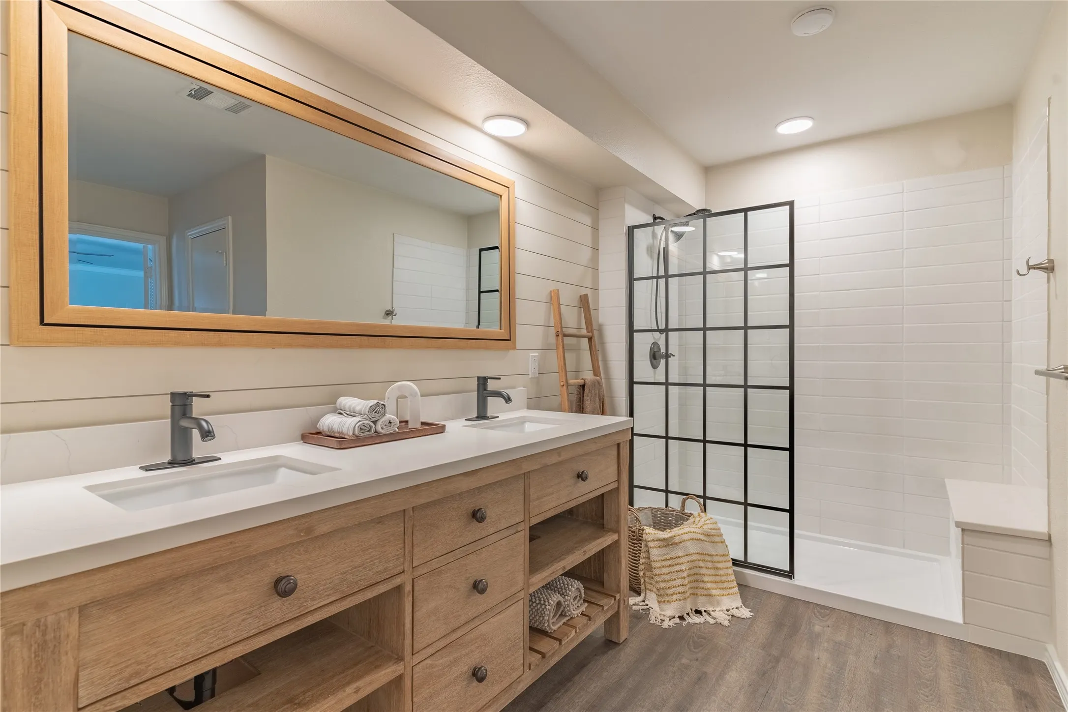 Dual vanity with natural wood-finish cabinetry, white countertop, and integrated sinks