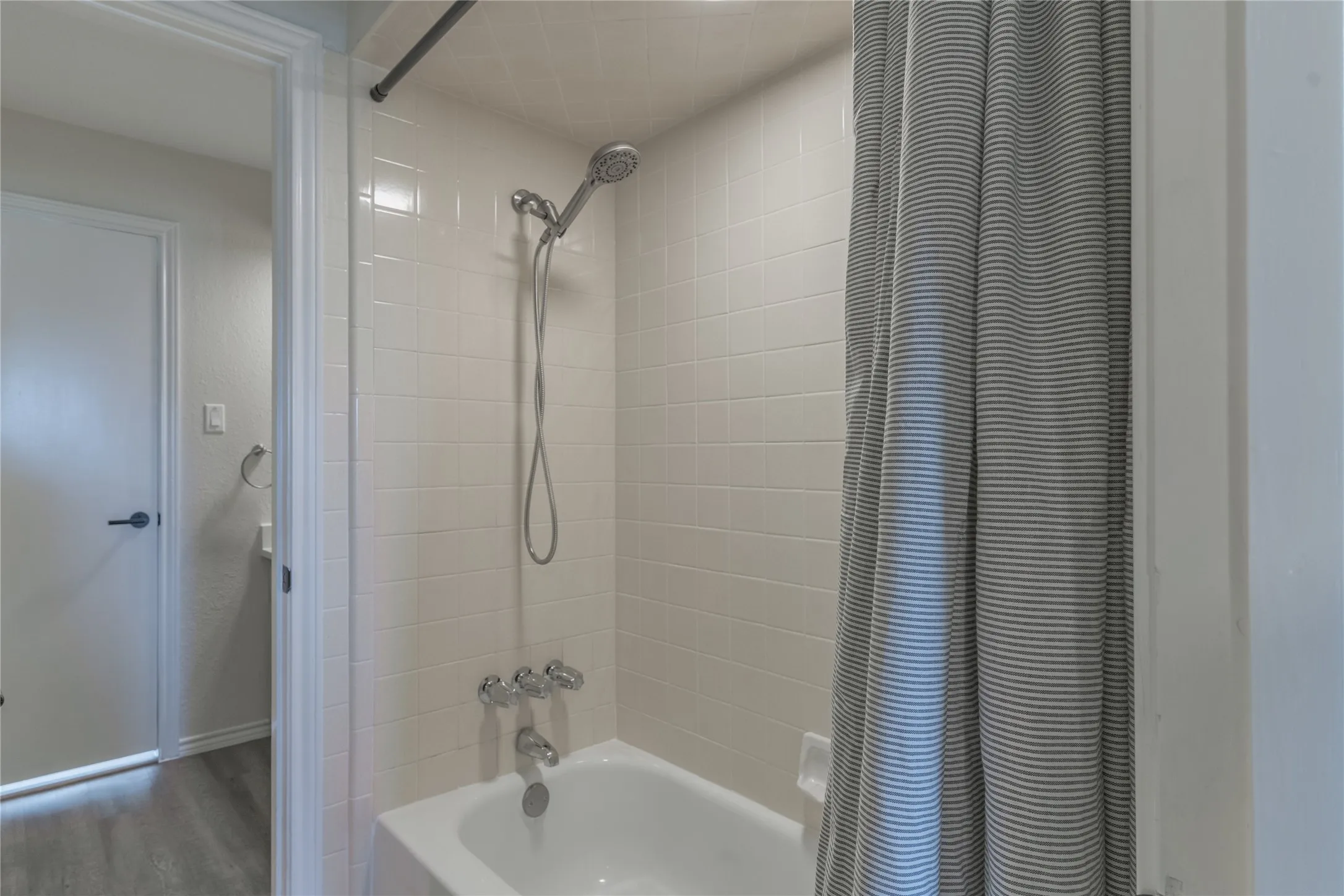 White subway tile shower surround with a fixed showerhead and hand shower